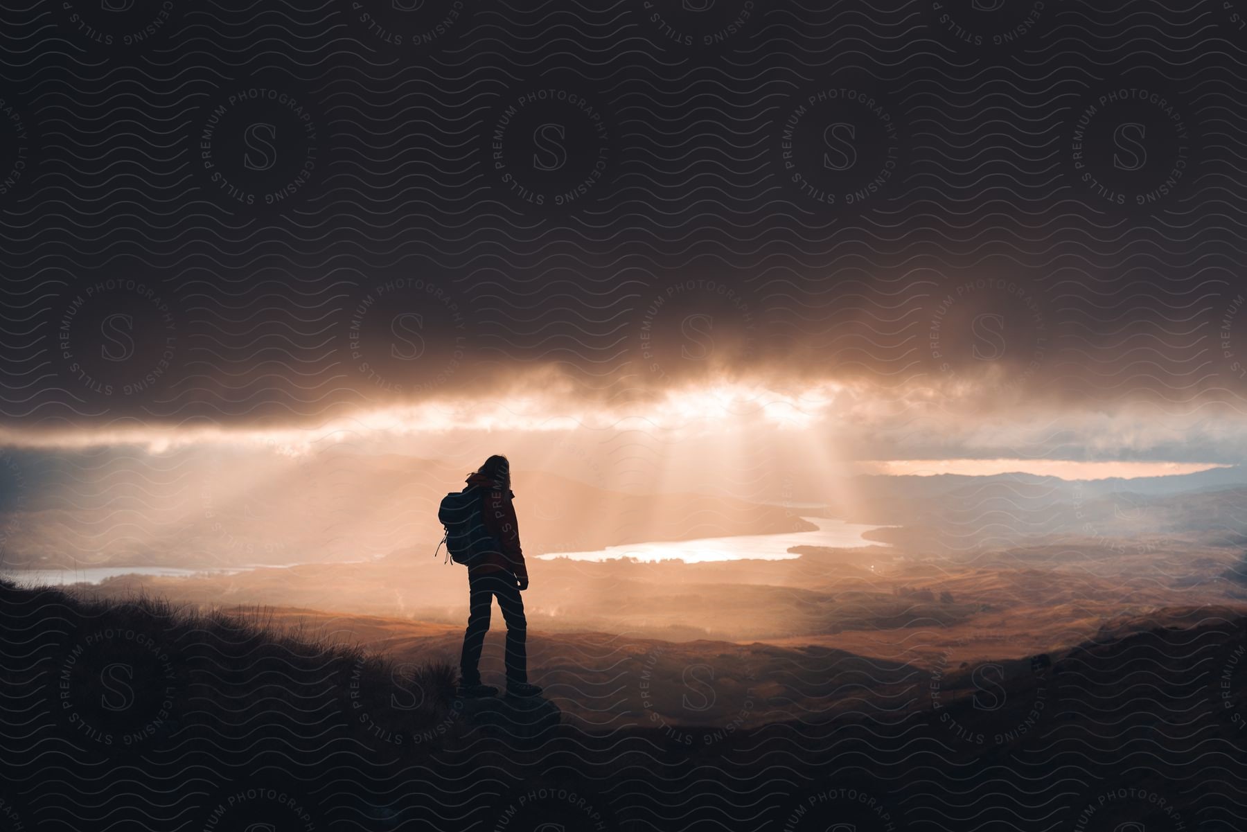 Stock photo of a hiker standing on a hill overlooking a river in scotland