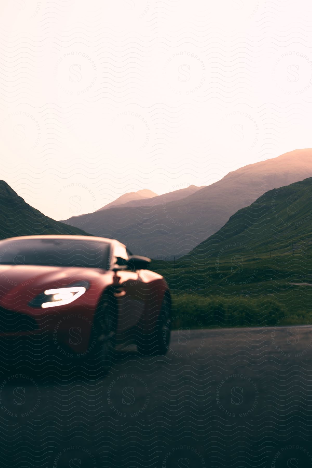 A sport car parked near mountains with the sun setting