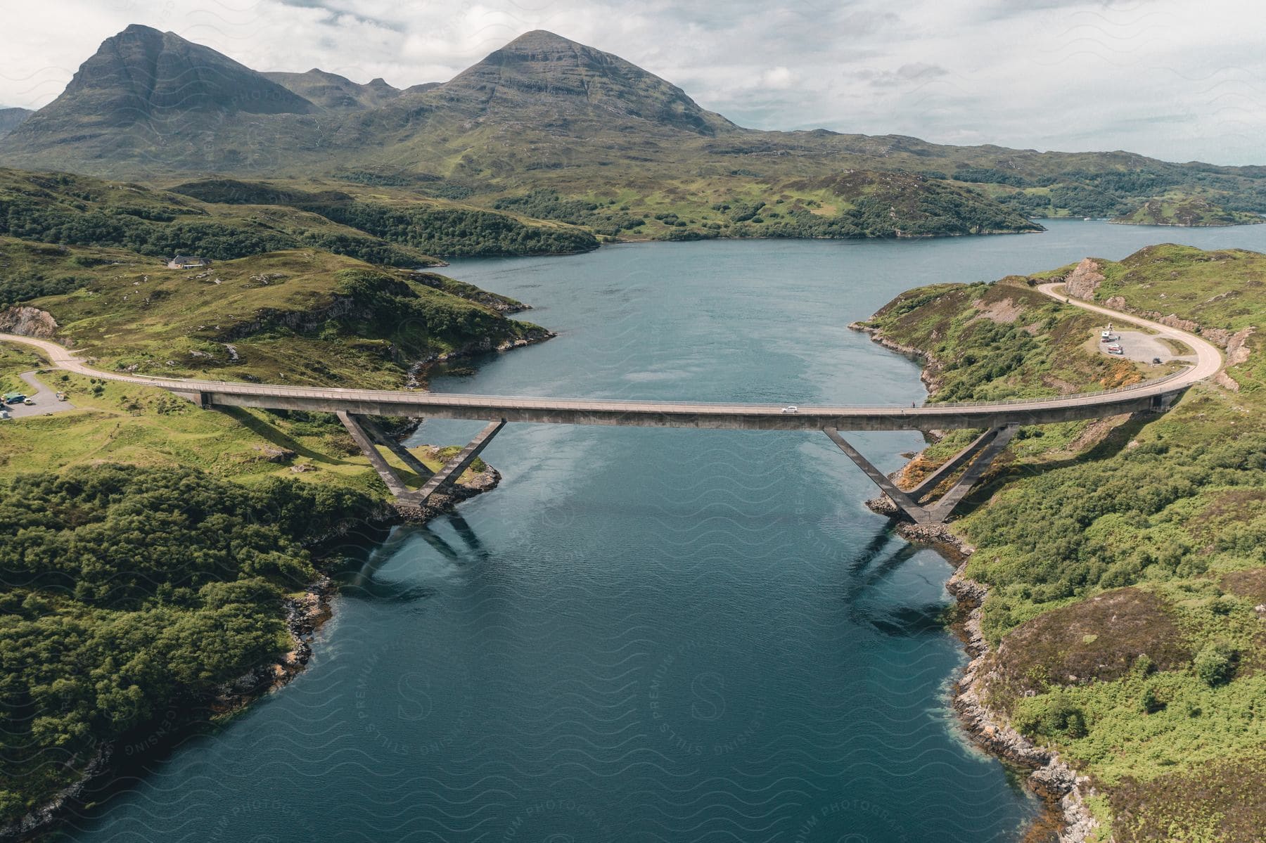 An aerial shot of a bridge over water with a mountain backdrop