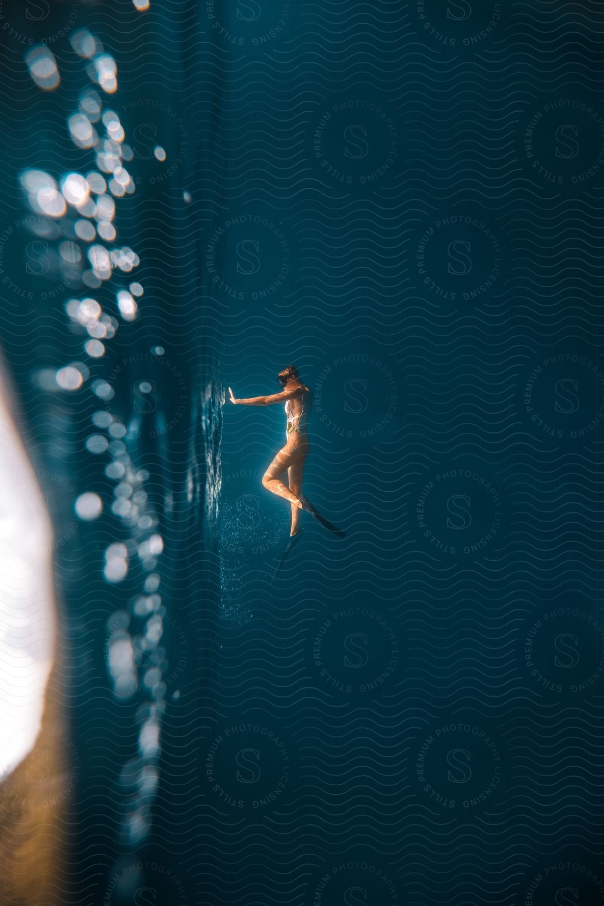 A woman swimming underwater wearing goggles with the image turned sideways