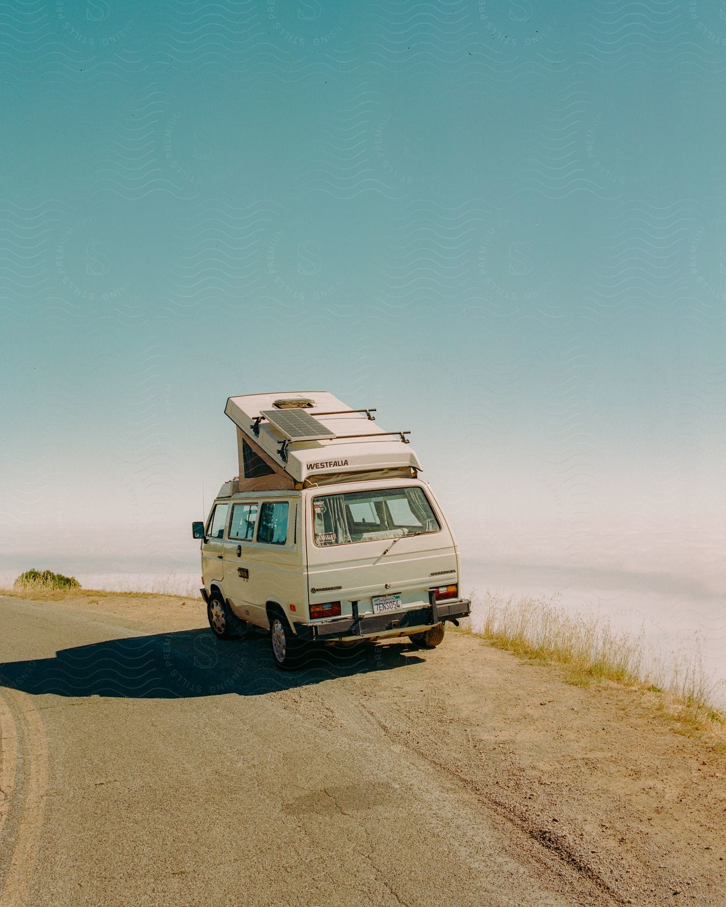 Camper van parked on side of the road overlooking the clouds below