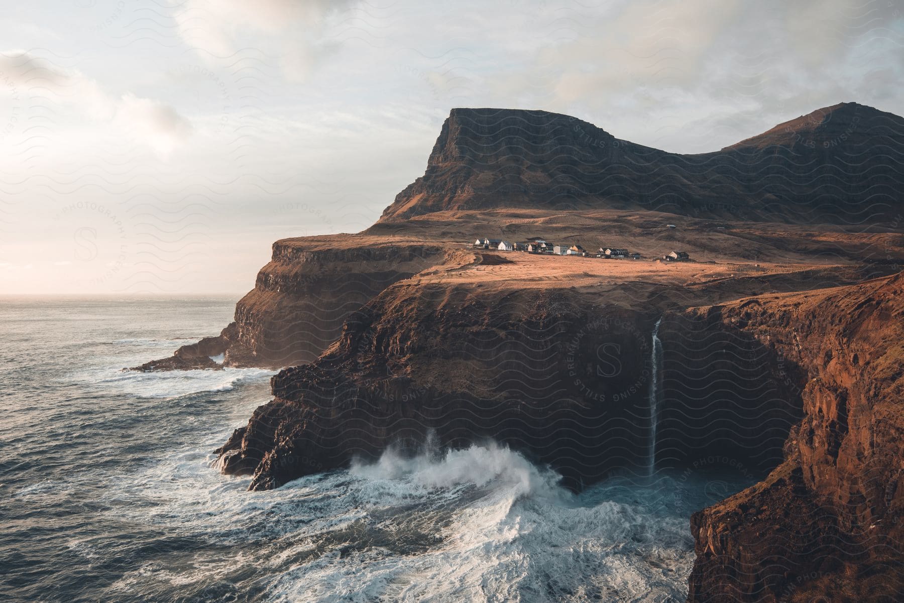 Brown water beside daytime waterfall and cluster of houses faroe islands