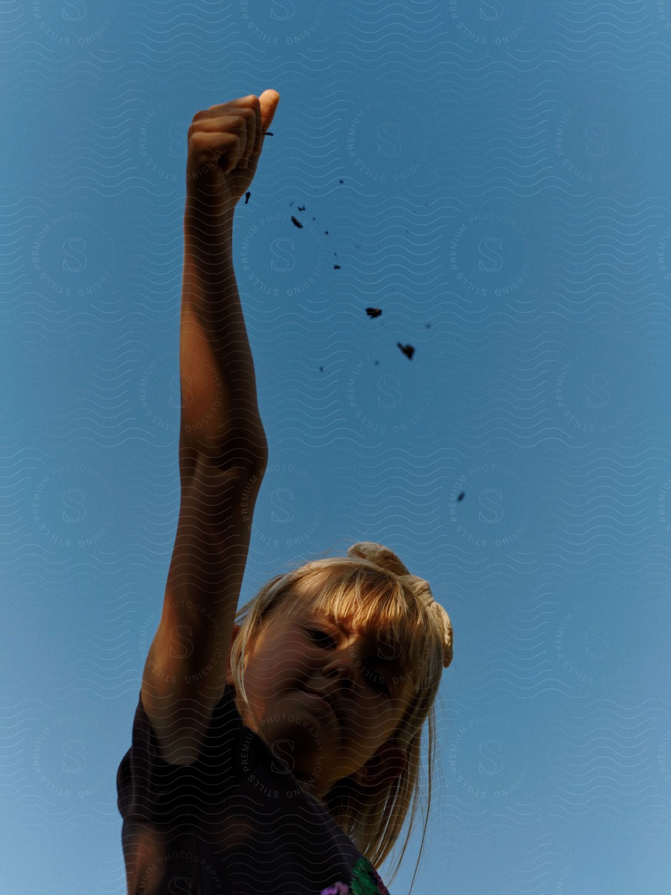 A determined girl raises her arm in the sky with a clenched fist