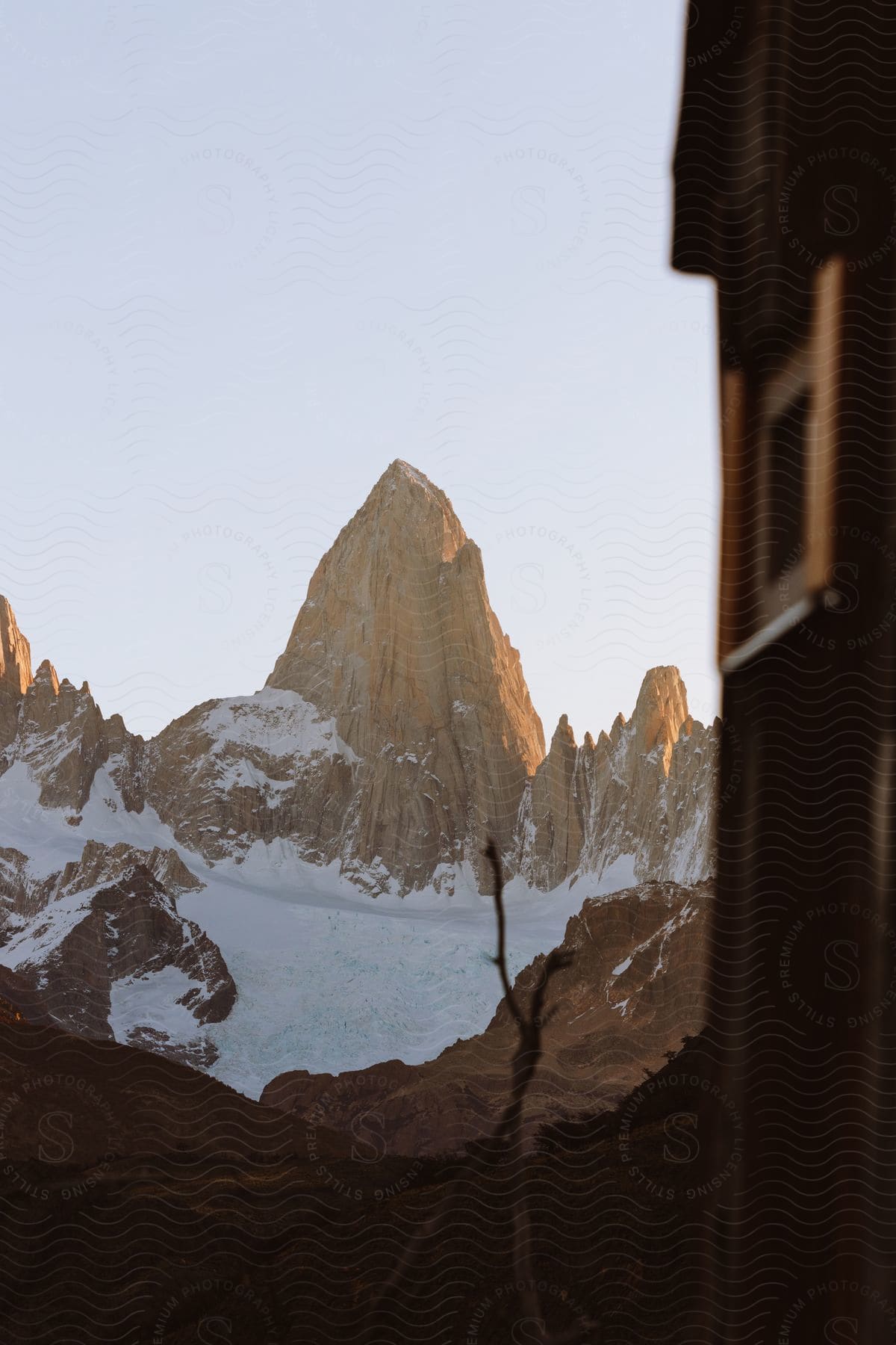 A snowcovered landscape with a large rock mountain towering over it