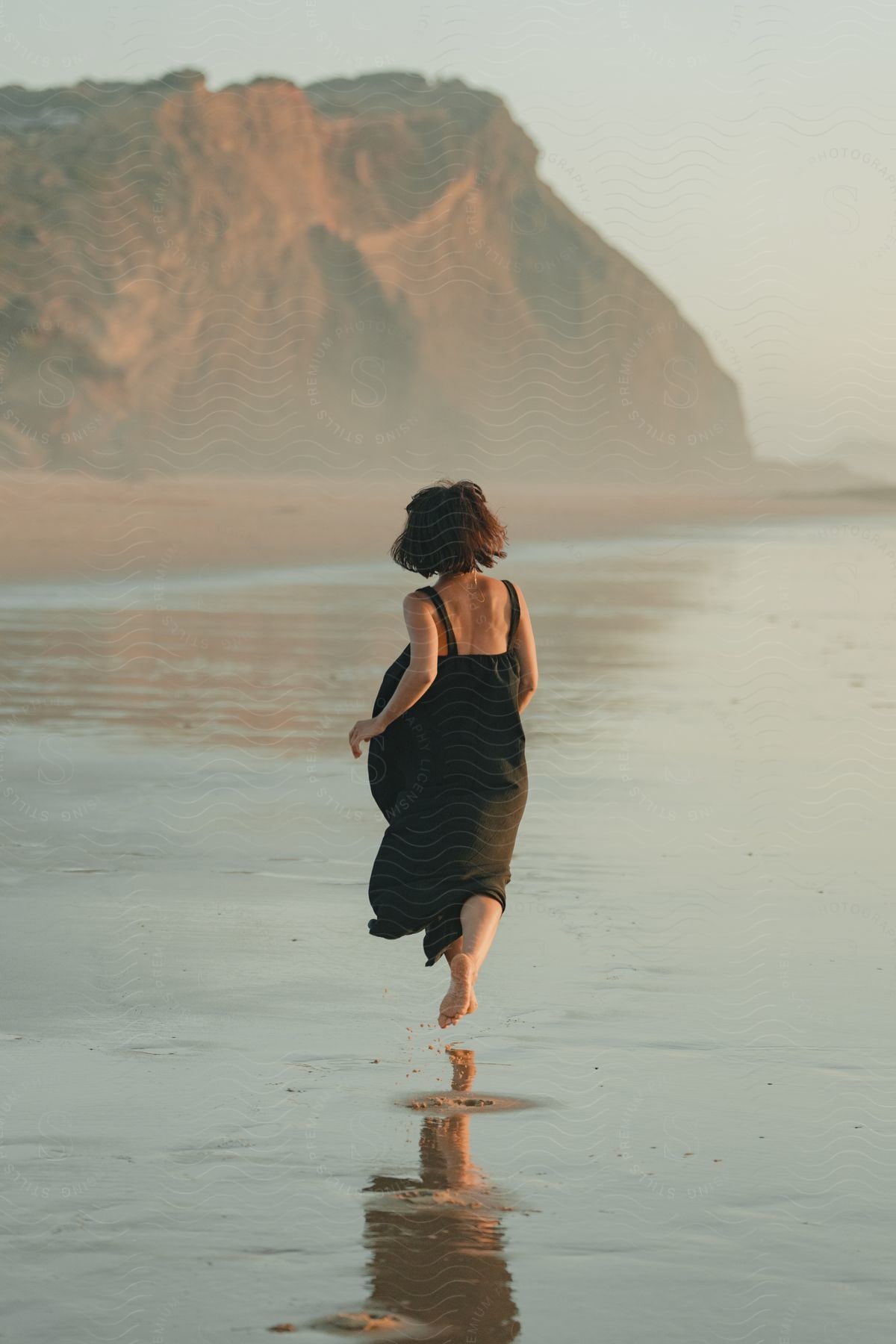 A woman running on the beach in a black dress