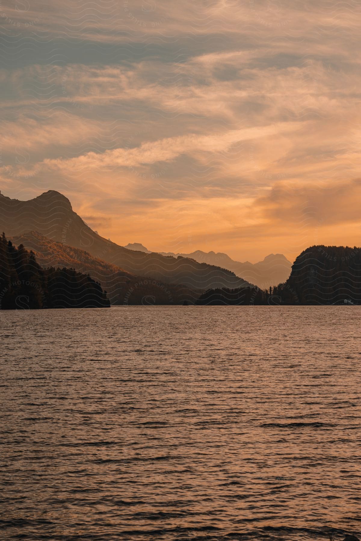 A dawn view of a lake with clouds and mountains in the background