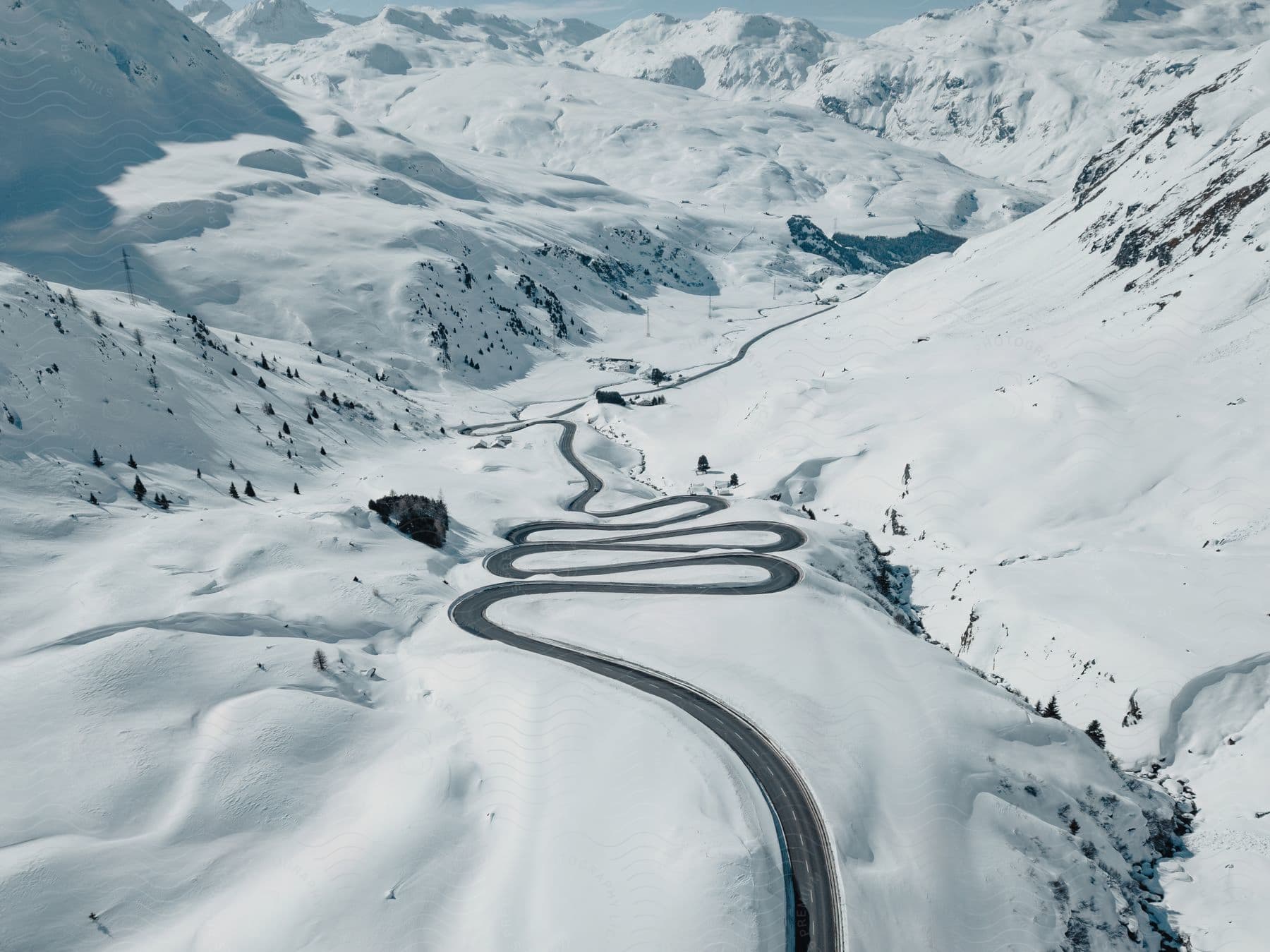 Winding mountain road with switchback curves through snowy landscape.