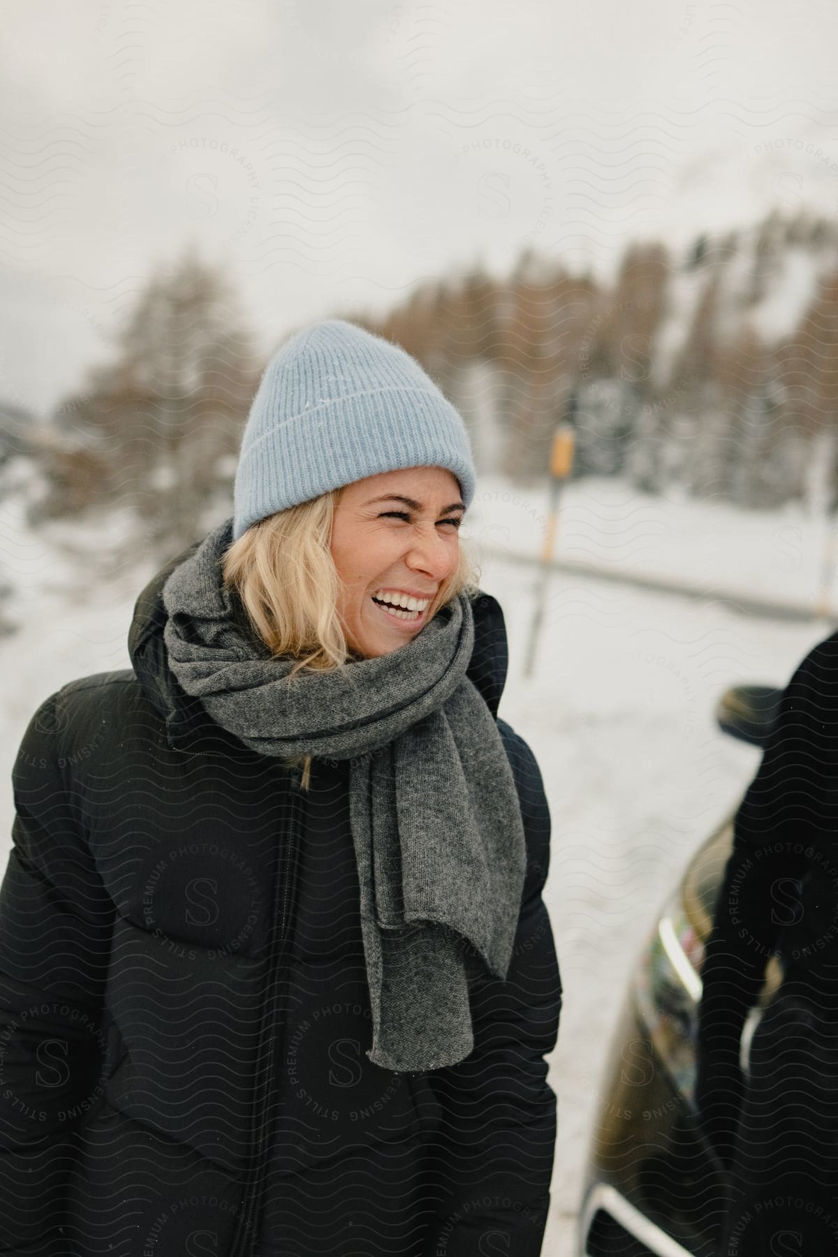 a young lady laughing while walking on a street covered in snow during the day