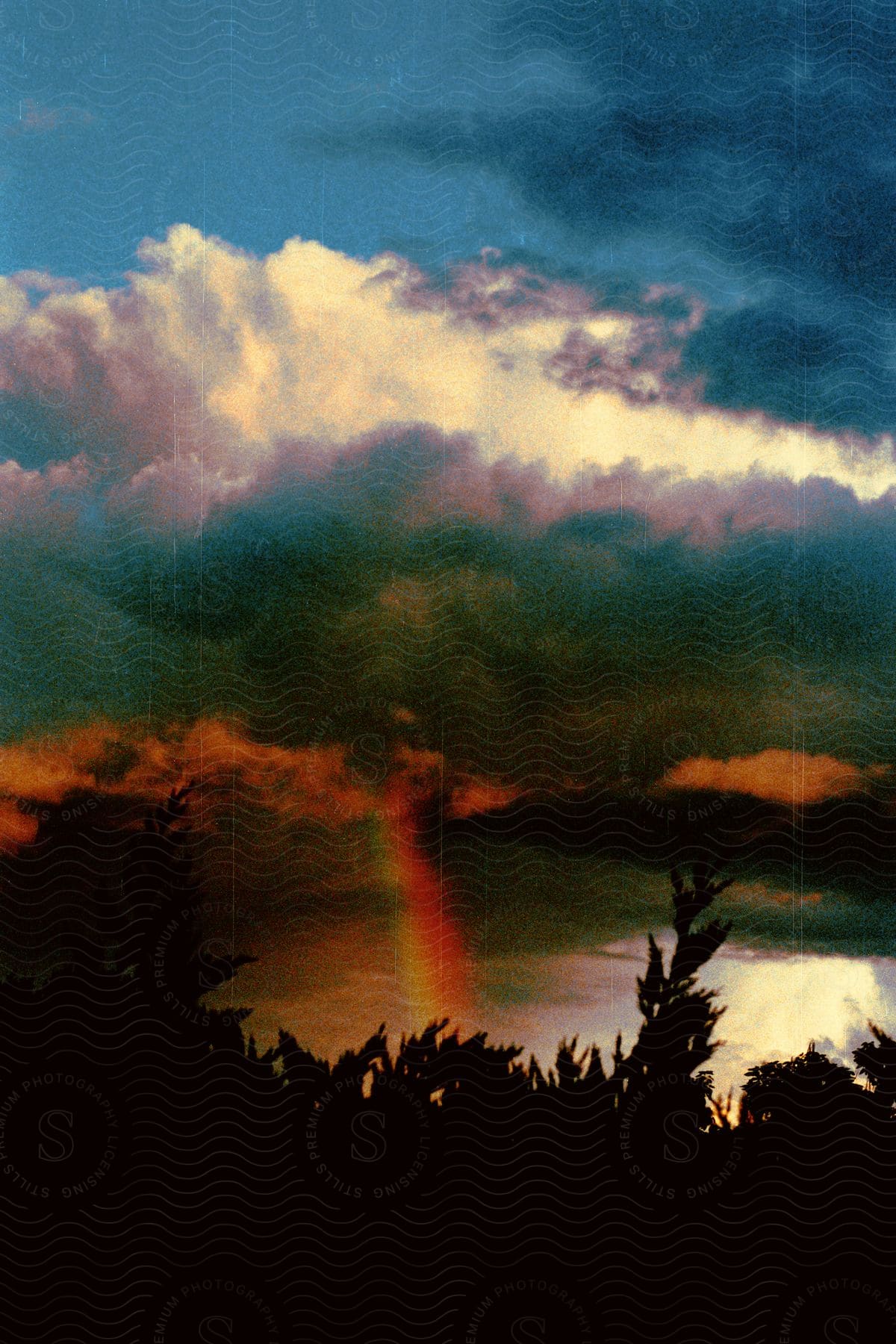 Wide shot of a tempest with a rainbow forming over a lake