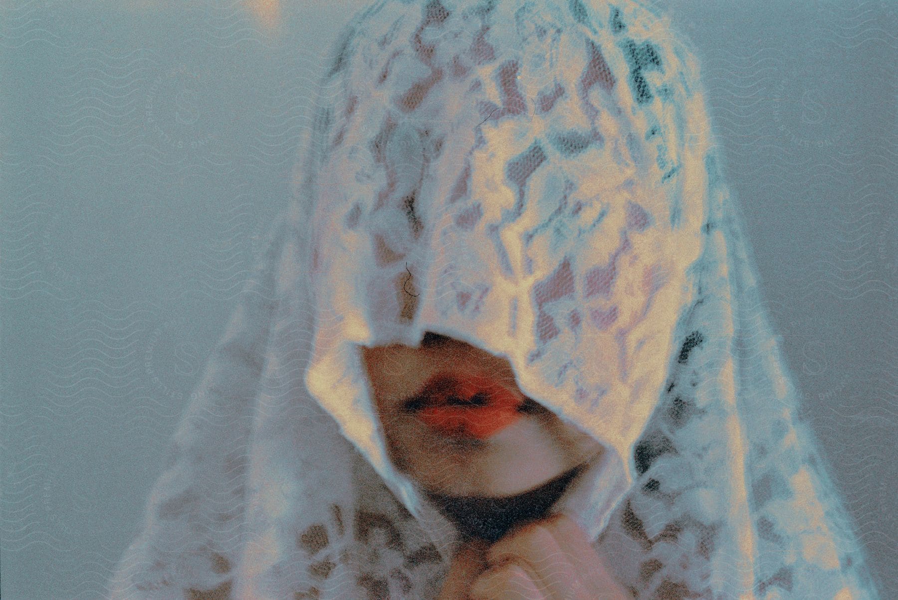 A woman standing indoors with lace material covering most of her face