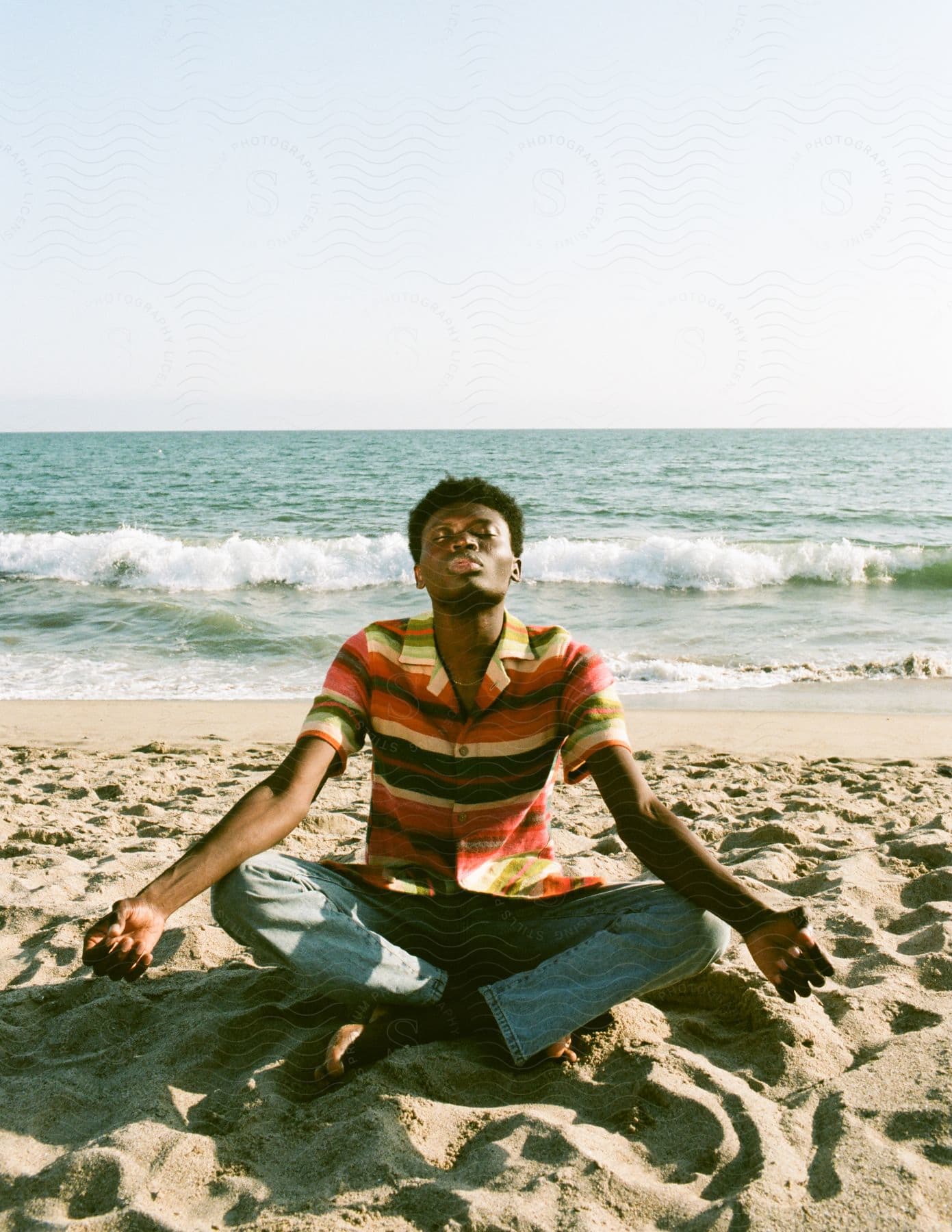 A happy teen boy sitting on a beach enjoying the outdoors