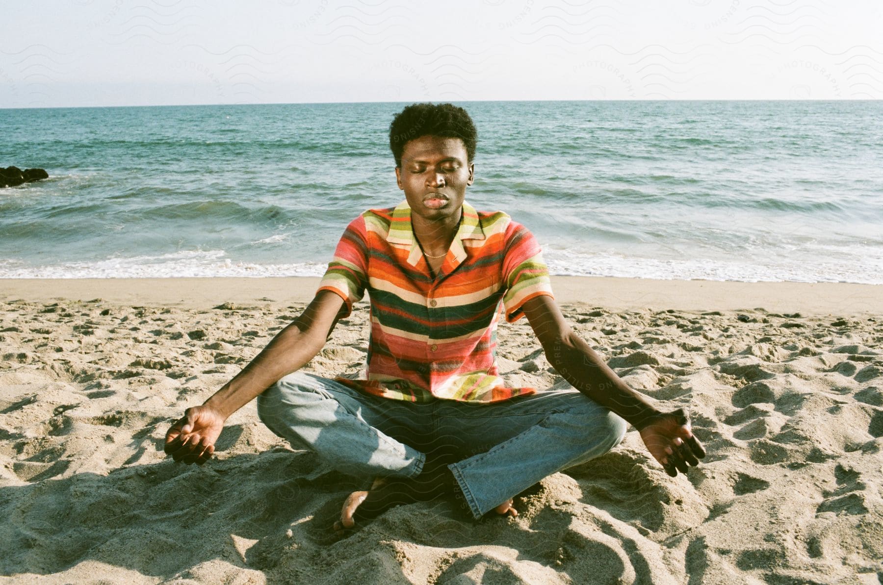 A man meditating on a beach on a summer day