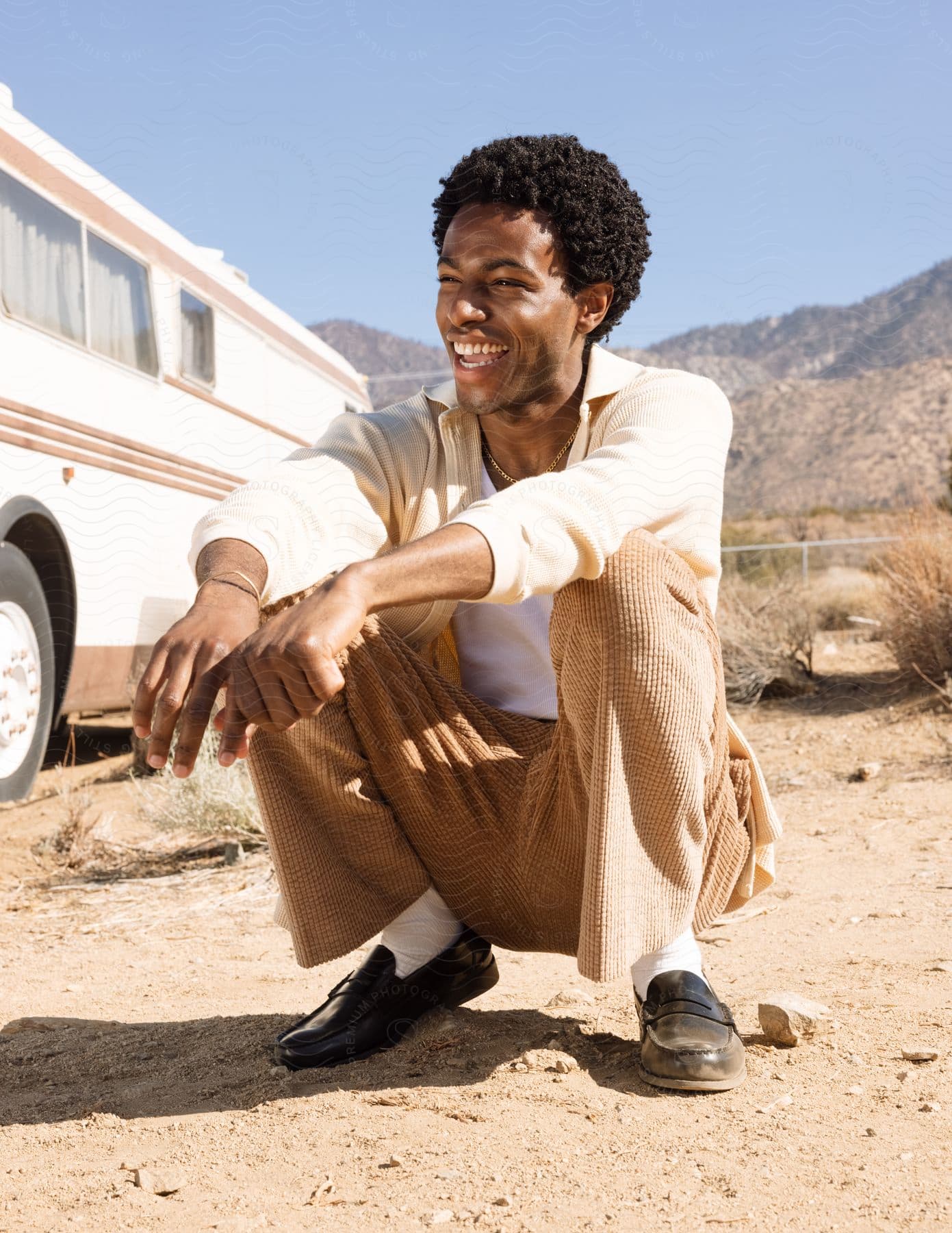 A man sitting in the desert laughing and having fun