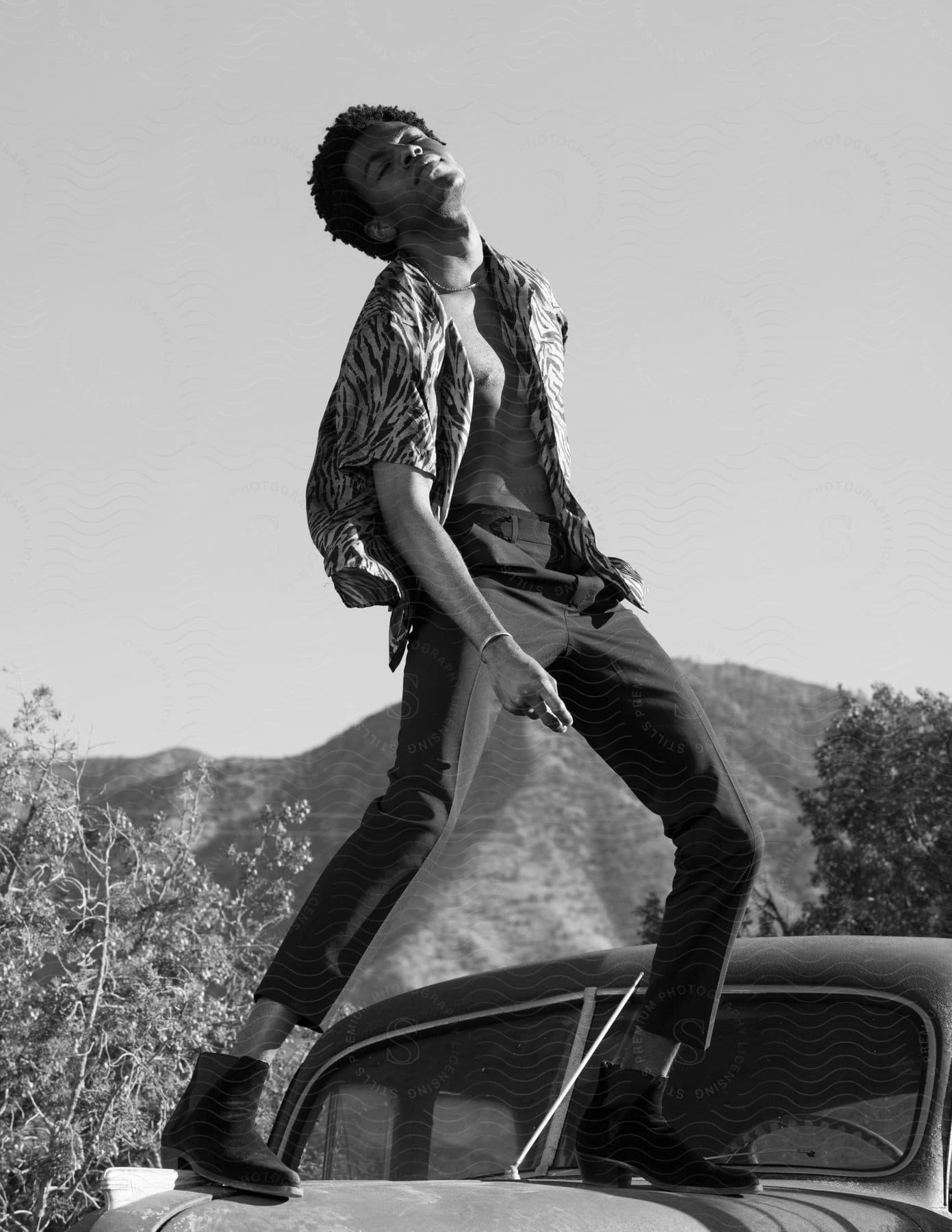 A man poses on the hood of a vintage car in the california desert