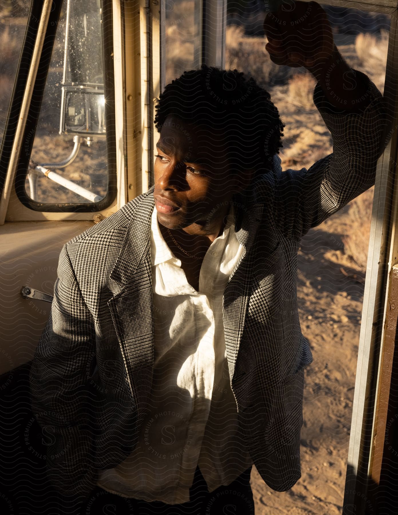 A young man stands at the entrance of a bus in the desert