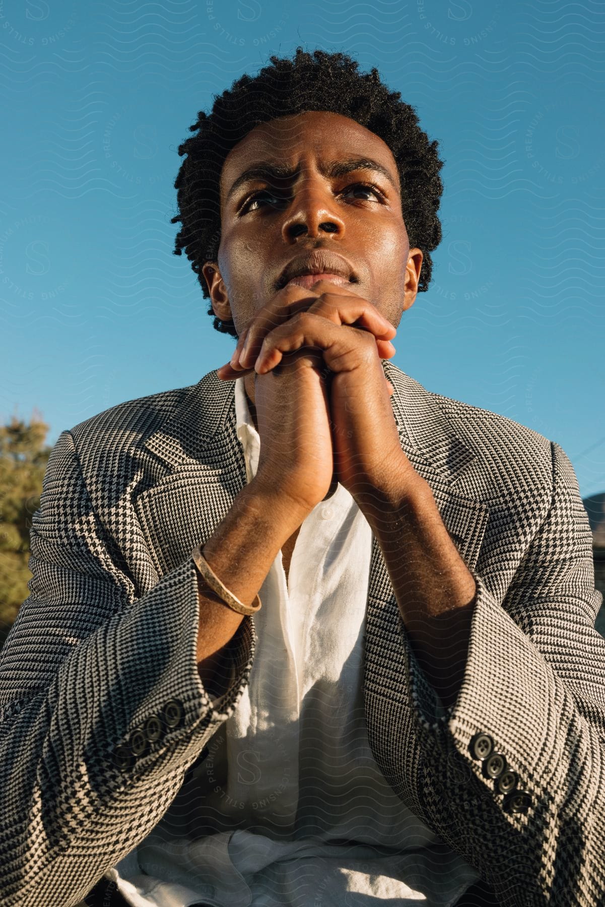 A man with black hair making a gesture against a sky backdrop in the desert