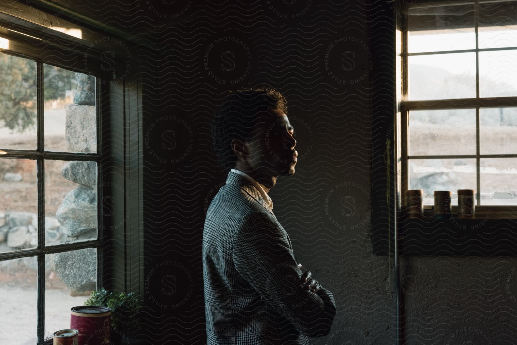 A man standing inside a house wearing a suit and looking contemplative