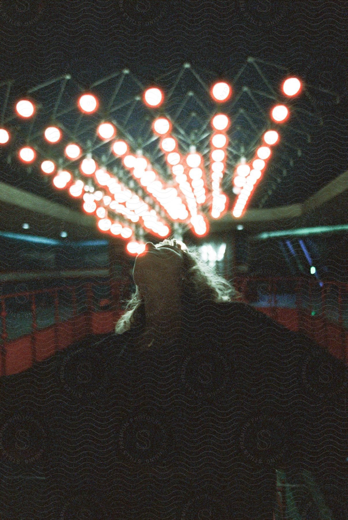 A woman looks up at night lights with her head back