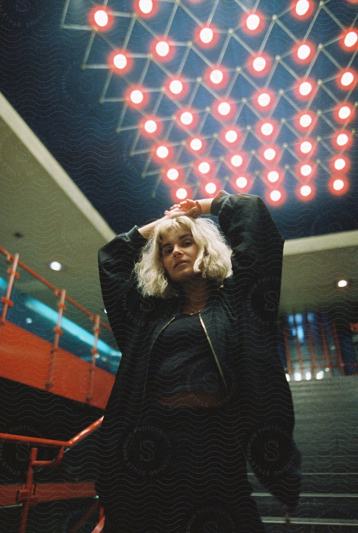 A female model poses with her arms above her head in front of a staircase