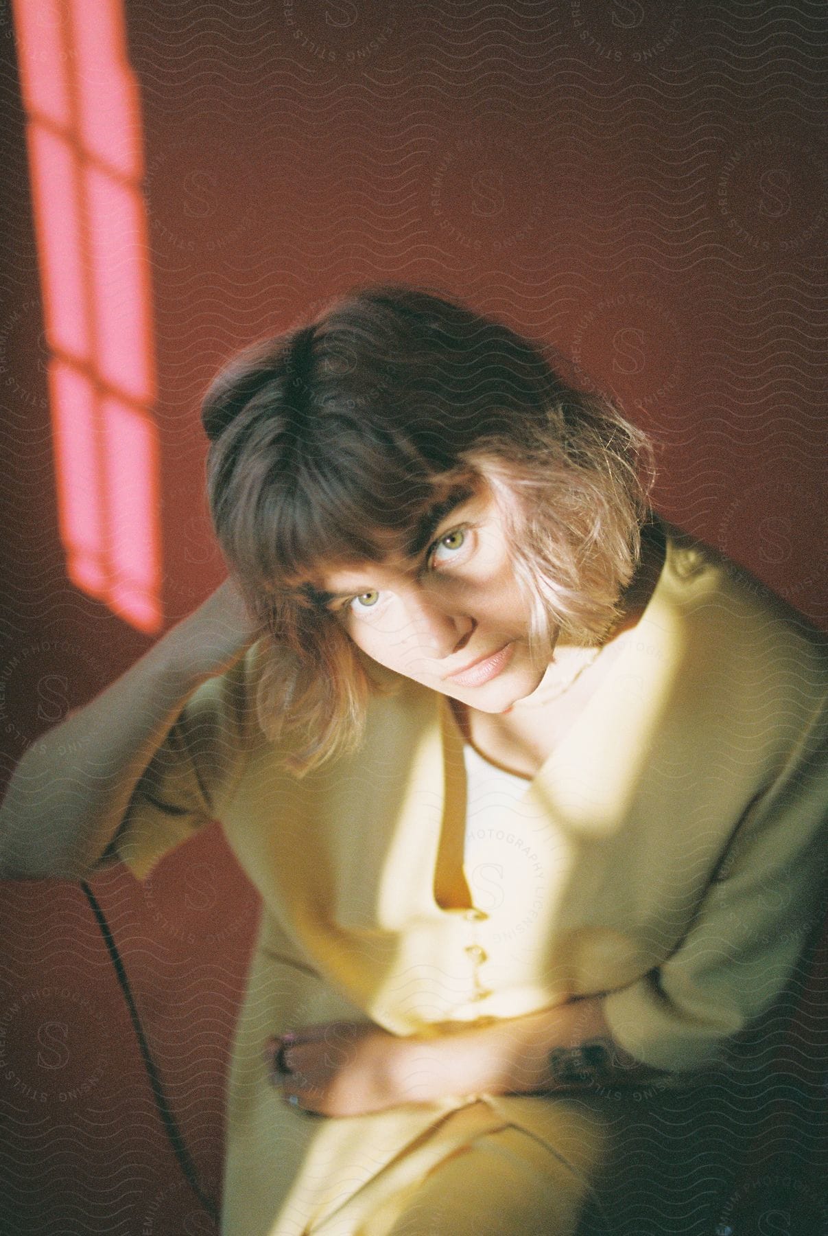 A Woman Wearing A Yellow Blouse Looks Up At The Camera In A Studio Portrait