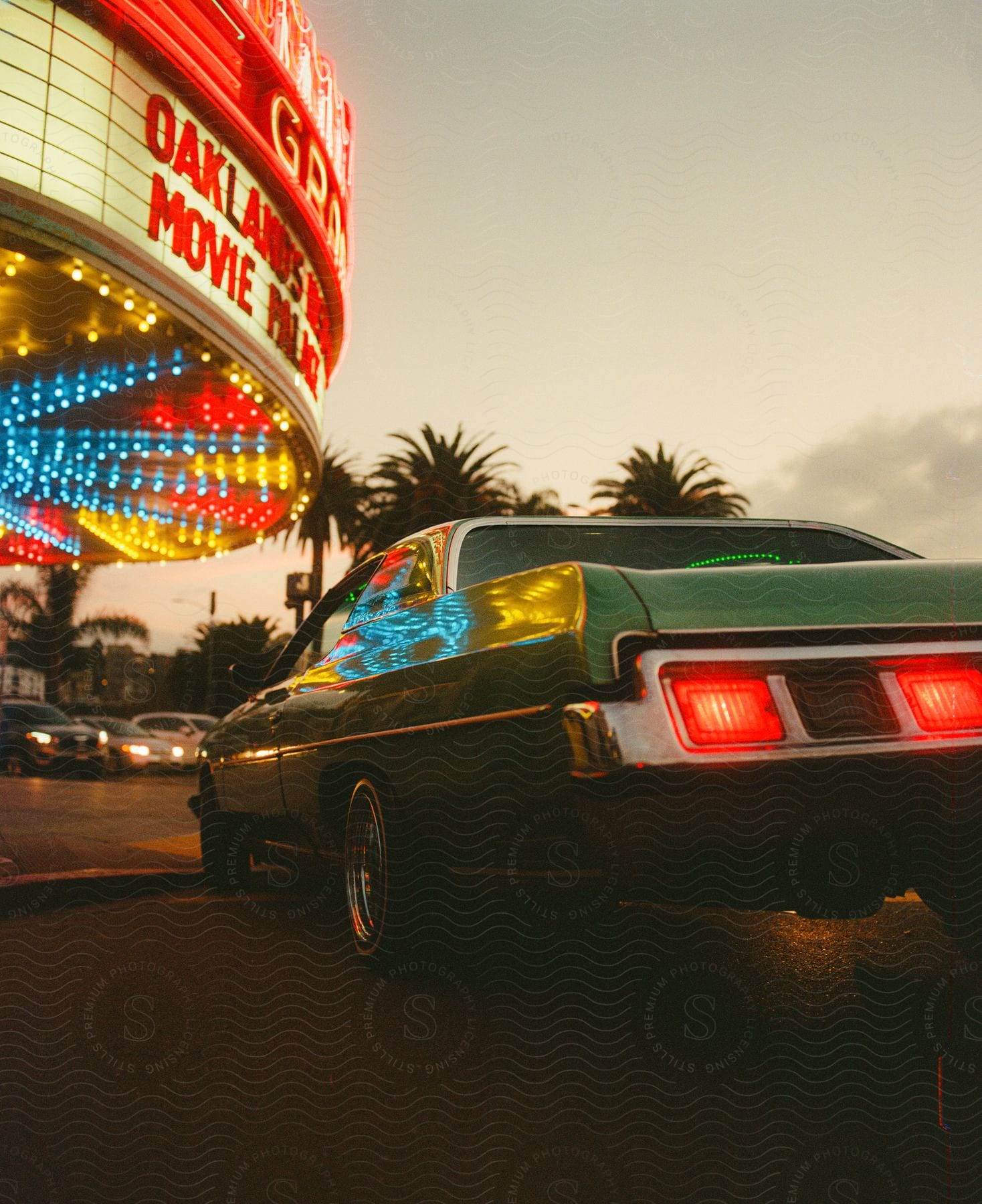 A classic car is parked outside a movie theater