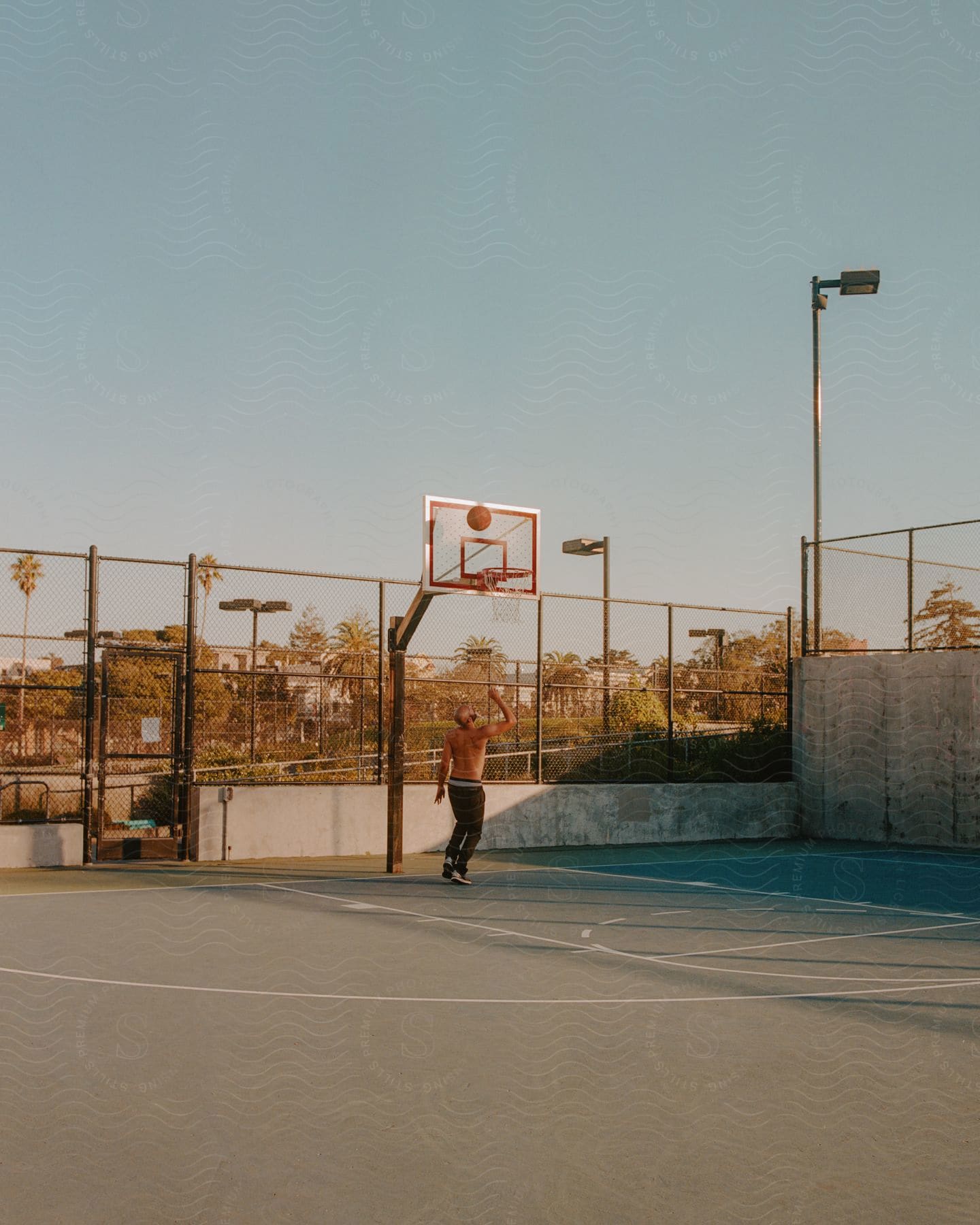 A man playing basketball alone during sunset