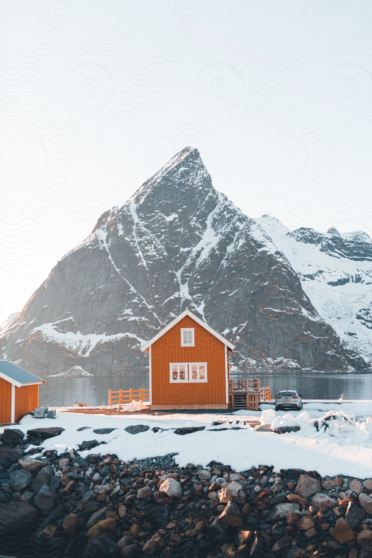 Landscape of red houses against a lake and snowy mountain ridge