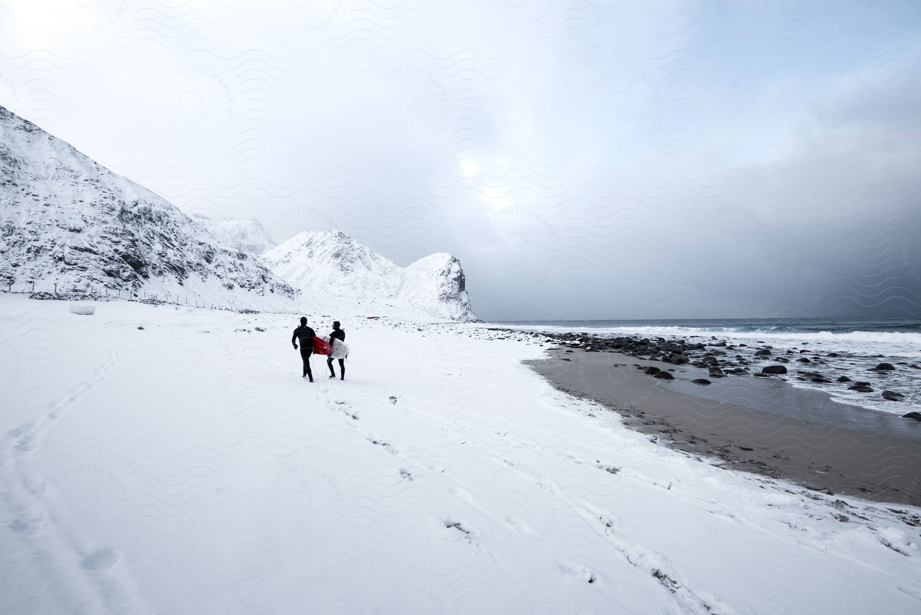 Two men walking along a snowy beach in norway