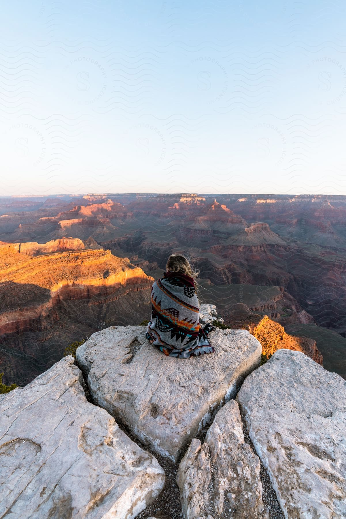 Girl looking at the horizon of a large canyon above a rock