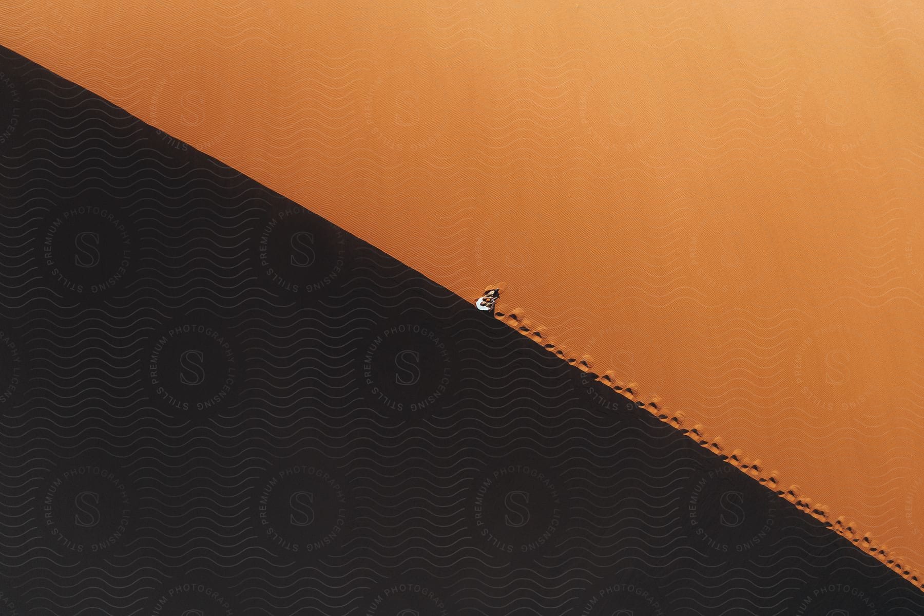 A Person Walking On The Edge Of A Desert Dune Seen From Above