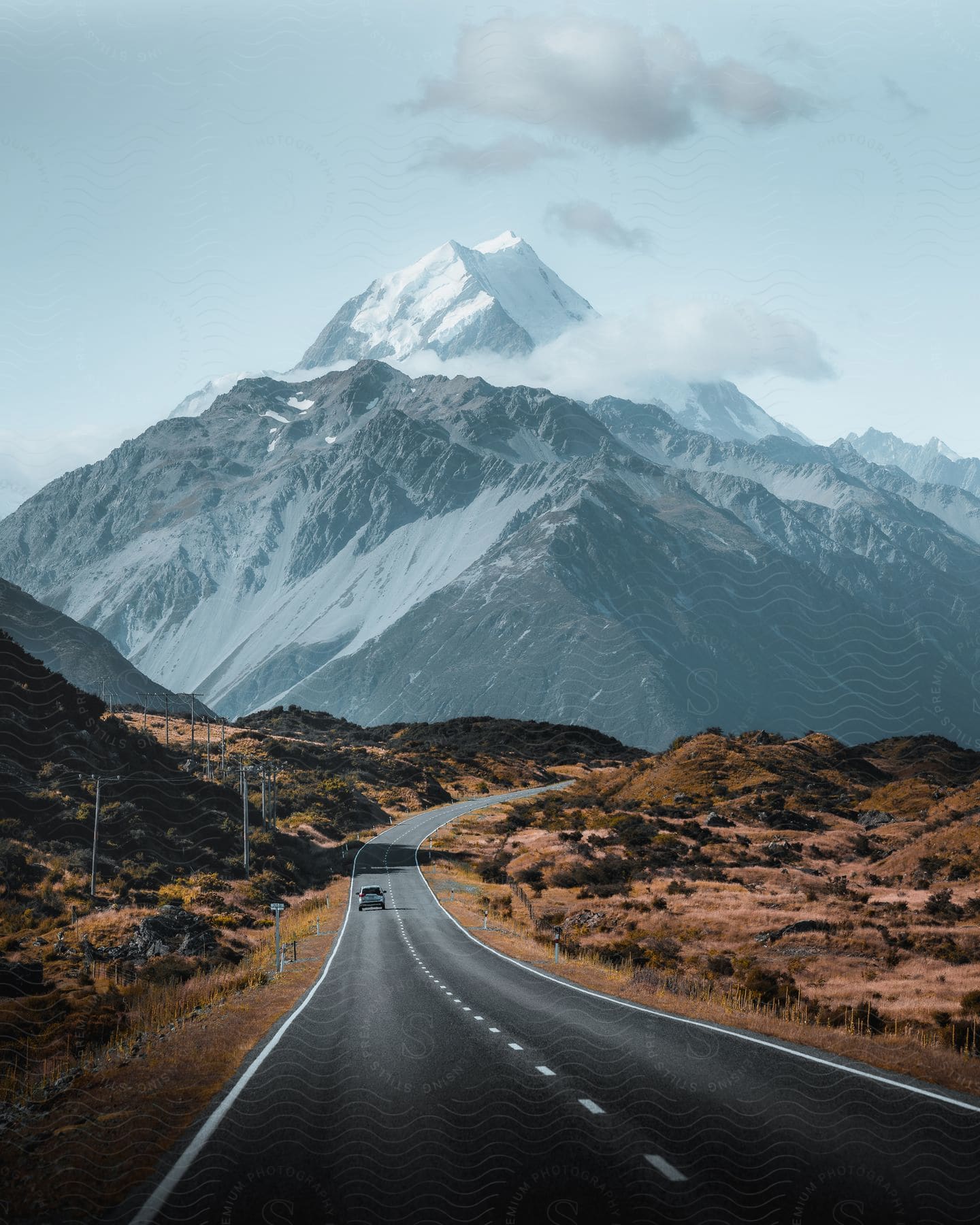 A truck travels on a mountain road with a snowcovered mountain in the distance