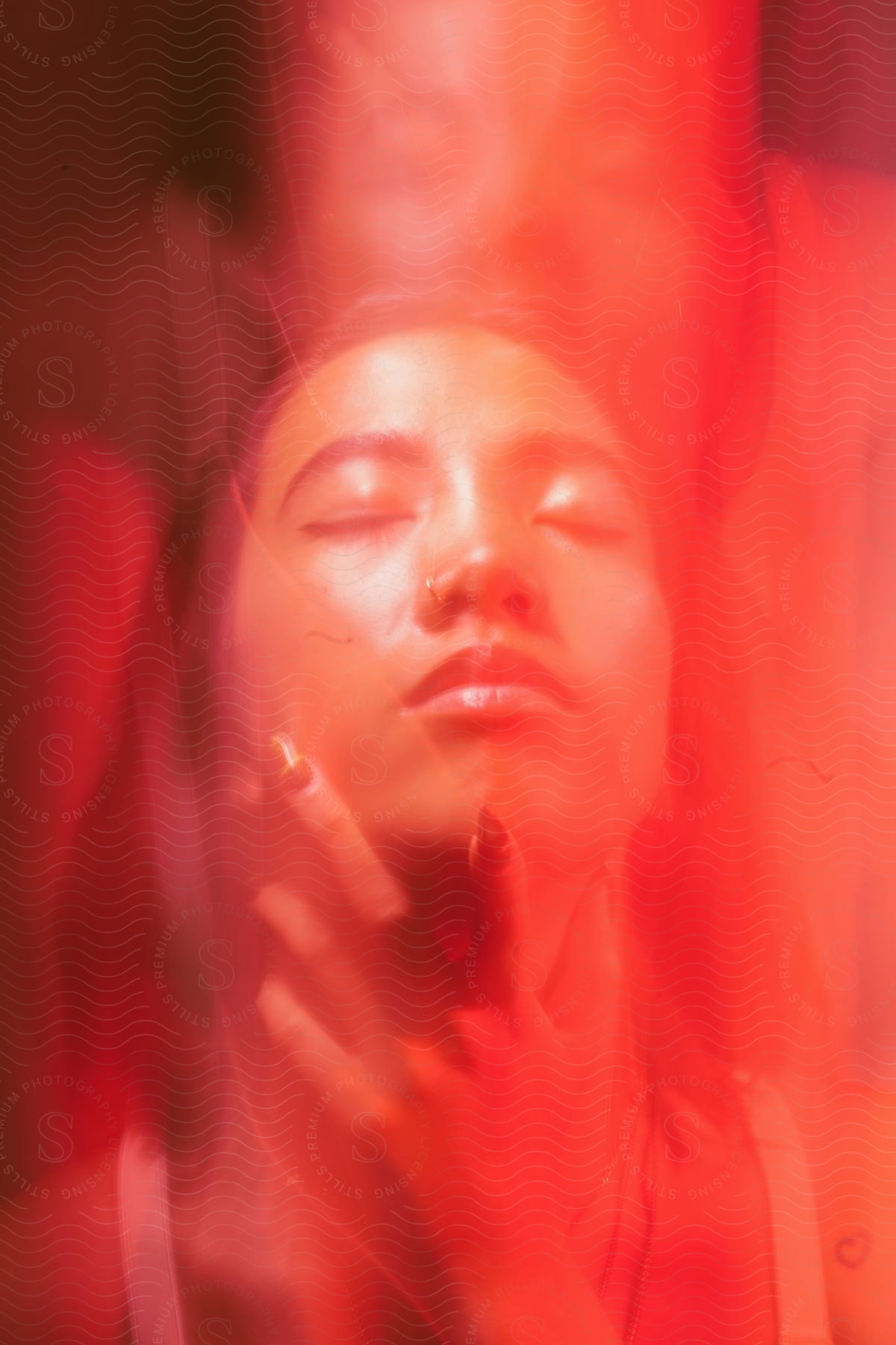 A female holds her face while another person stands behind her as red lighting covers them