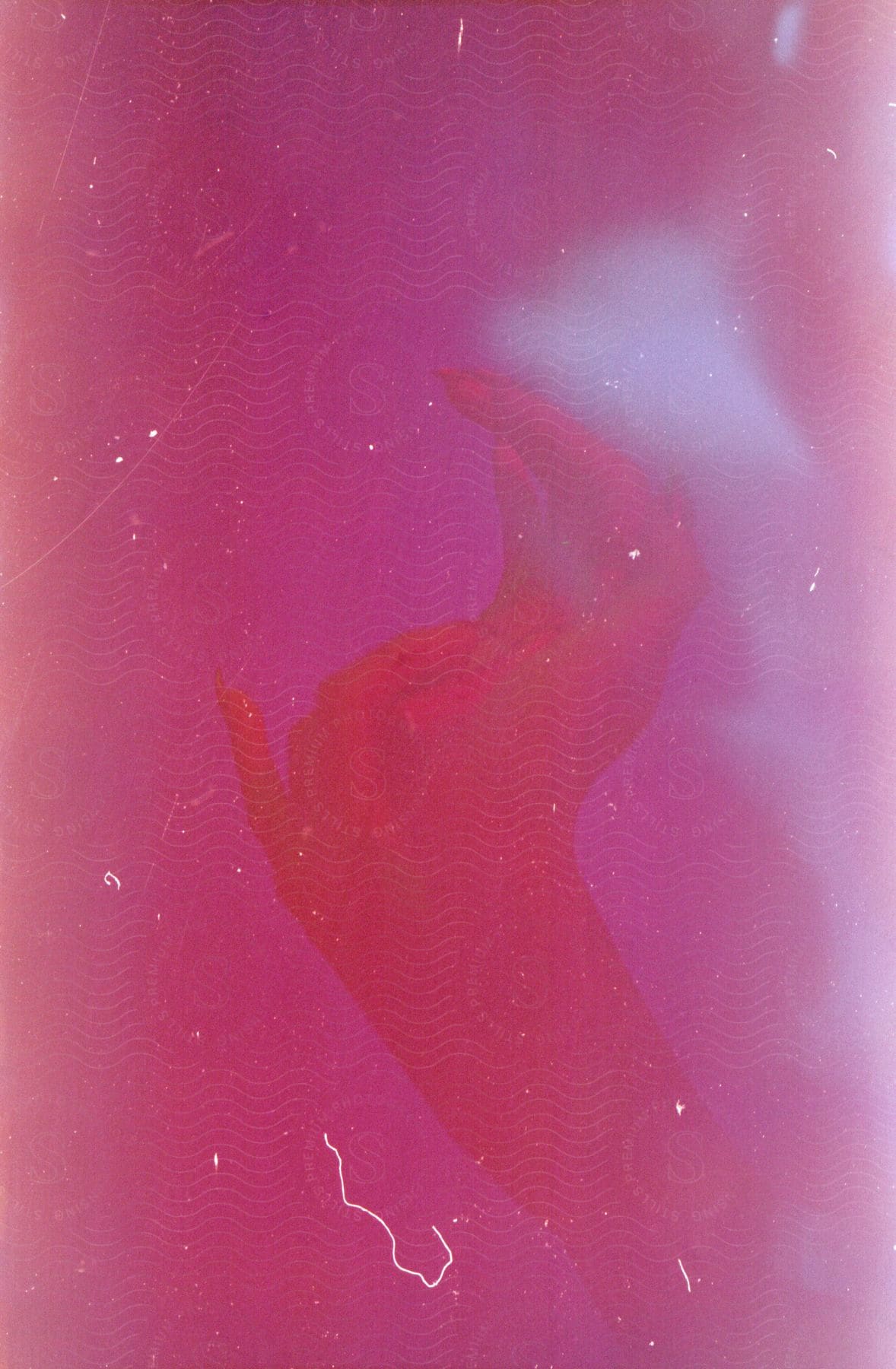 Overexposed close up of a young womans hands under red lights