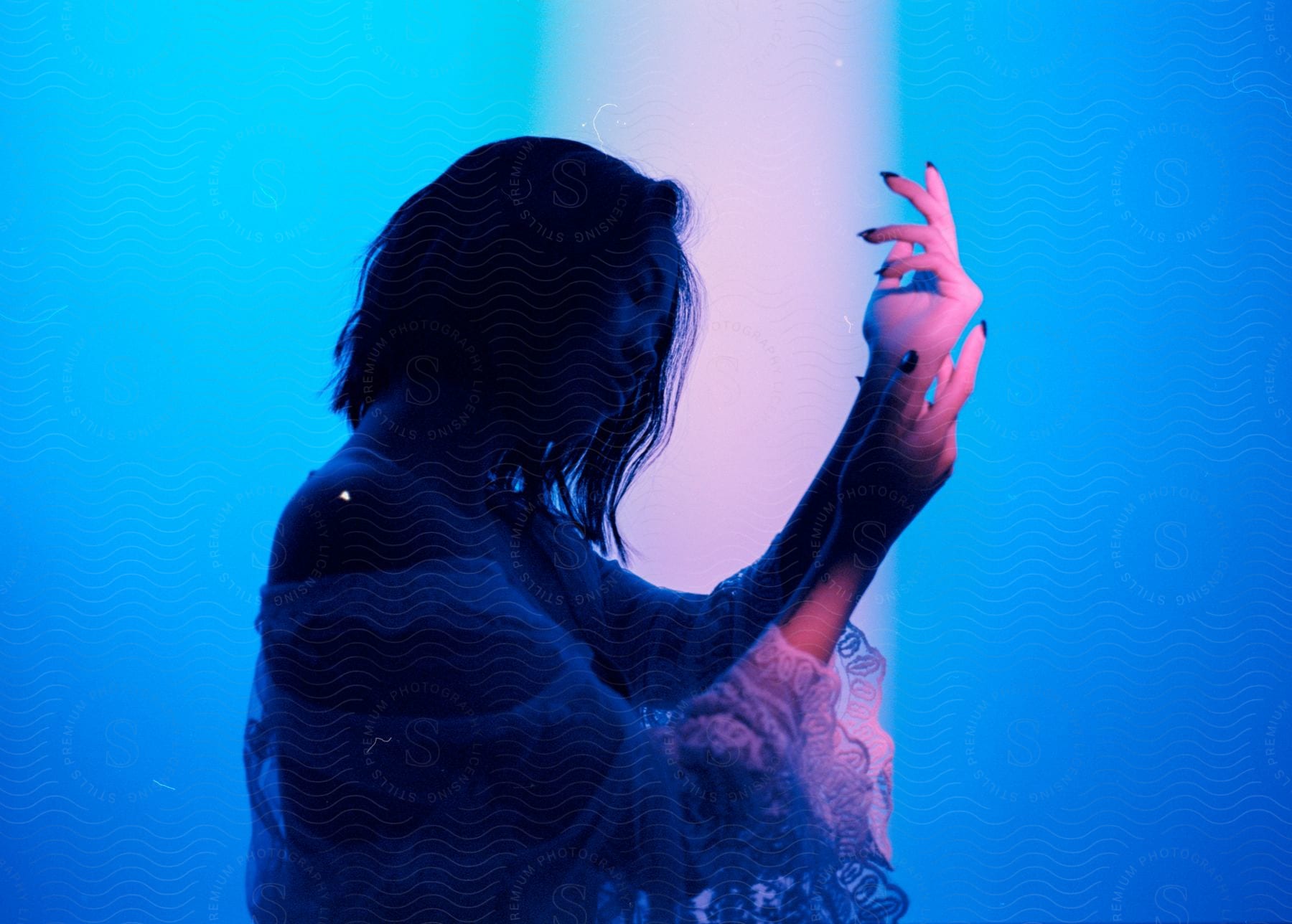 Woman with dark hair and white dress poses against a blue background