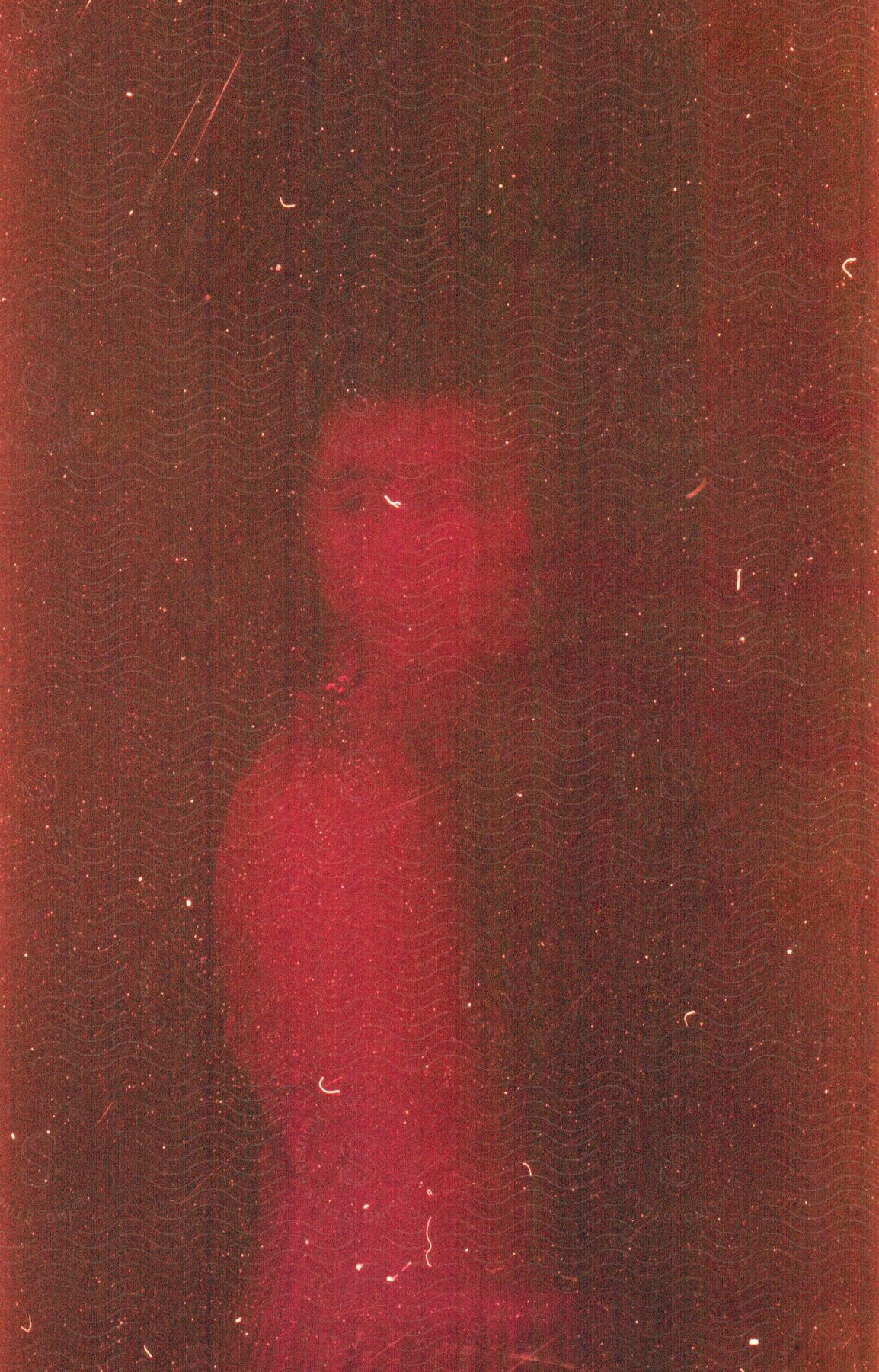 Woman under red lights against a textured surface in multiple exposure