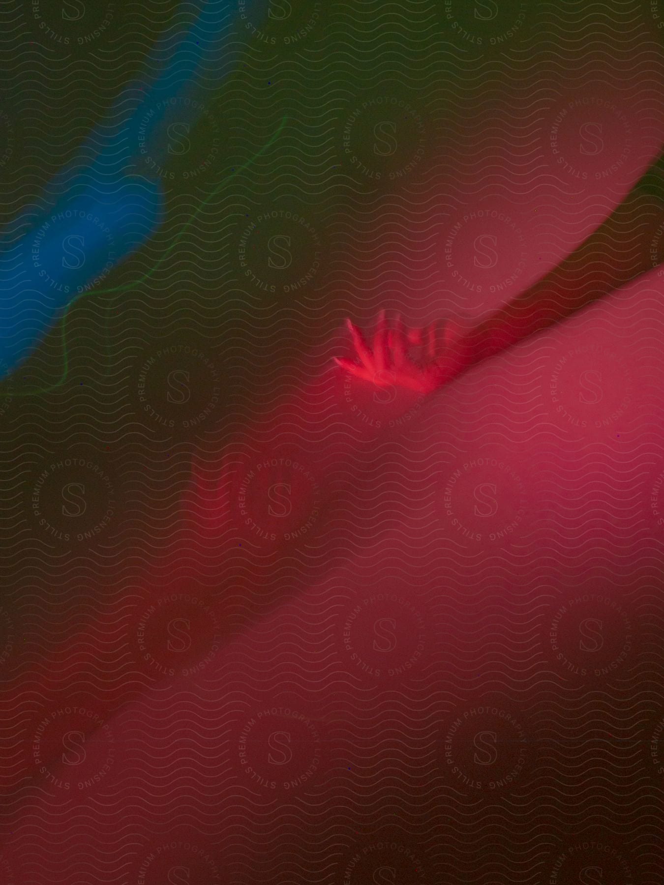 Blurry hand of a woman moving against a dark red background