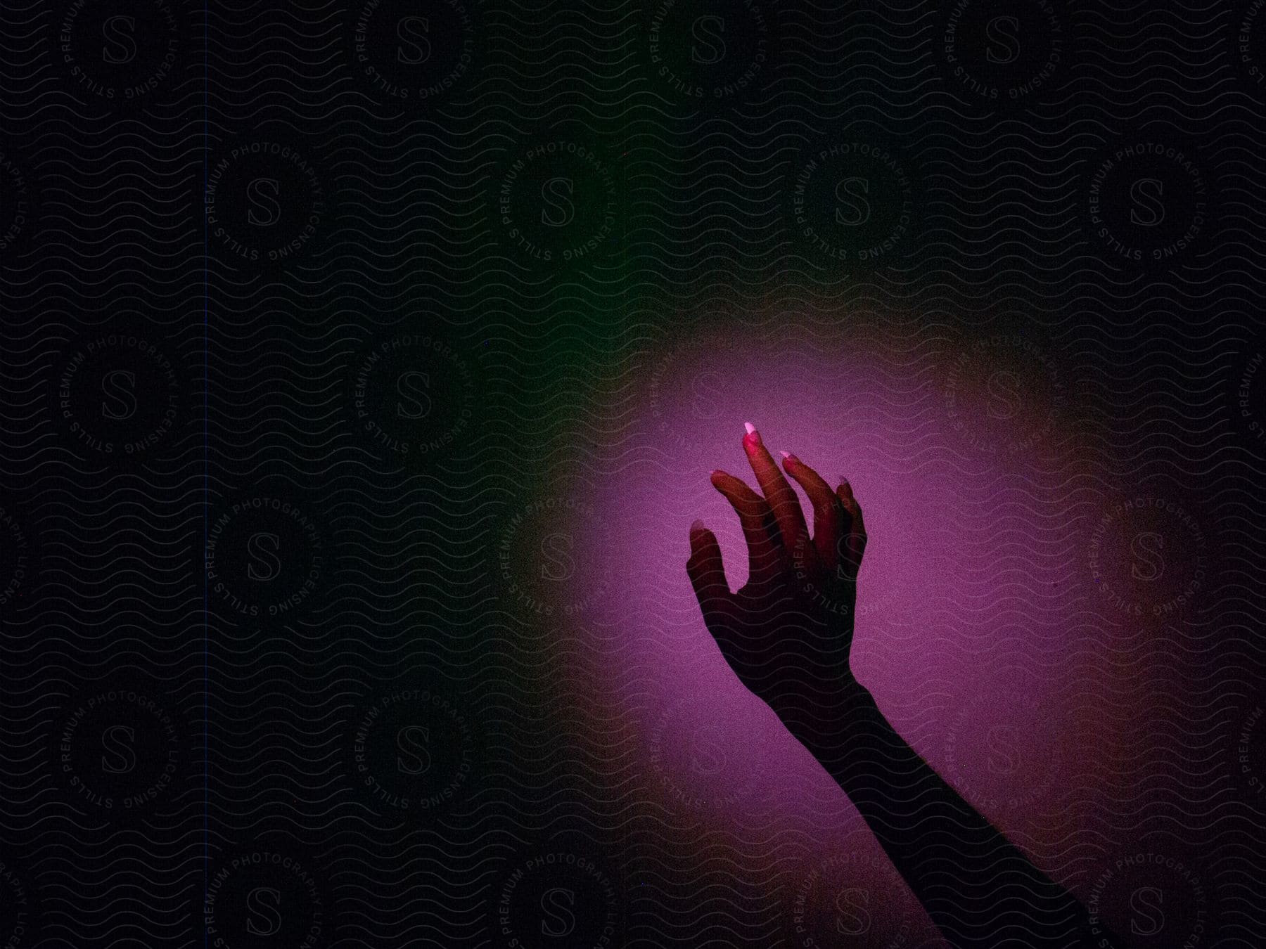 Female hand under intense purple lighting in a dark room