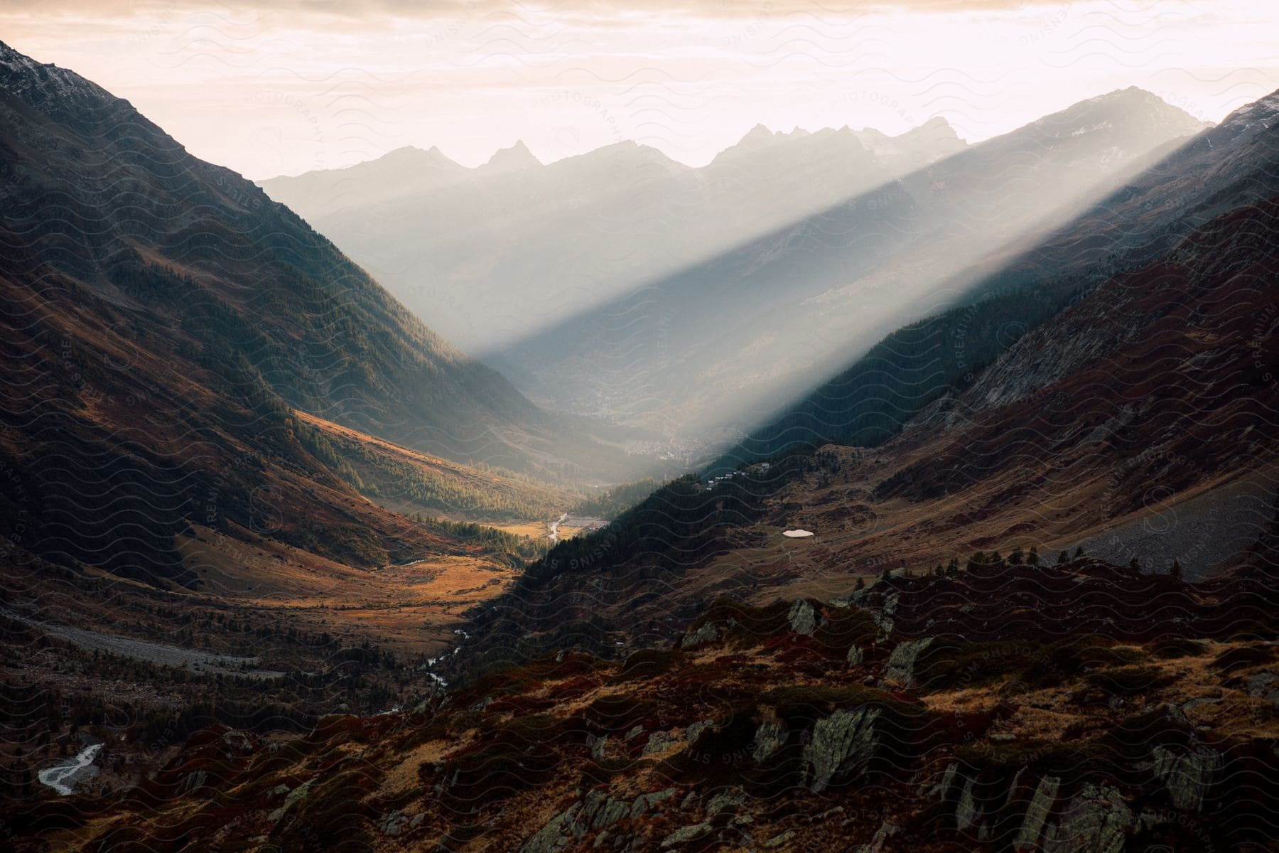 Rolling mountains and a valley with a river illuminated by sunlight