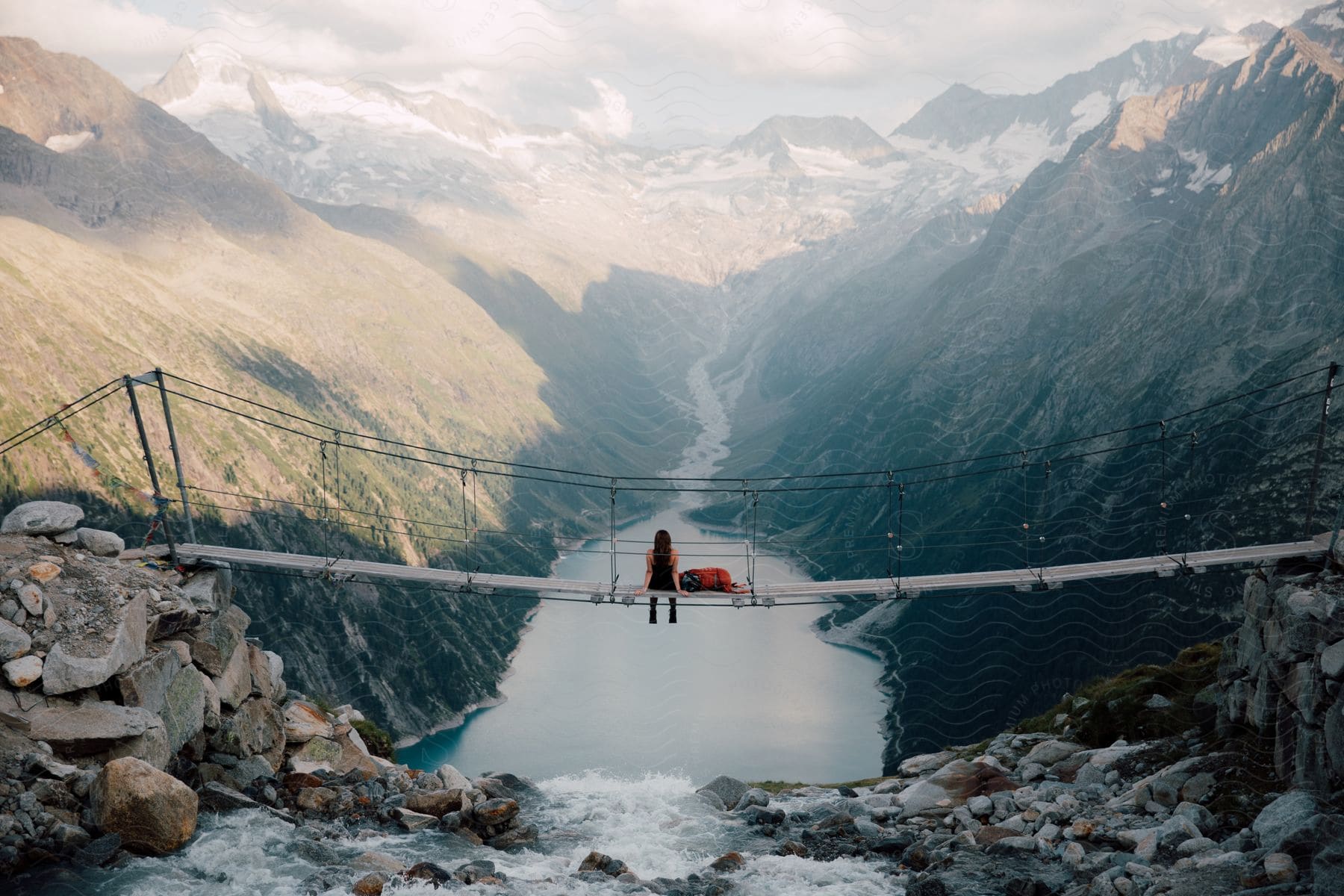 A woman sitting on a bridge near the mountains in the european alps