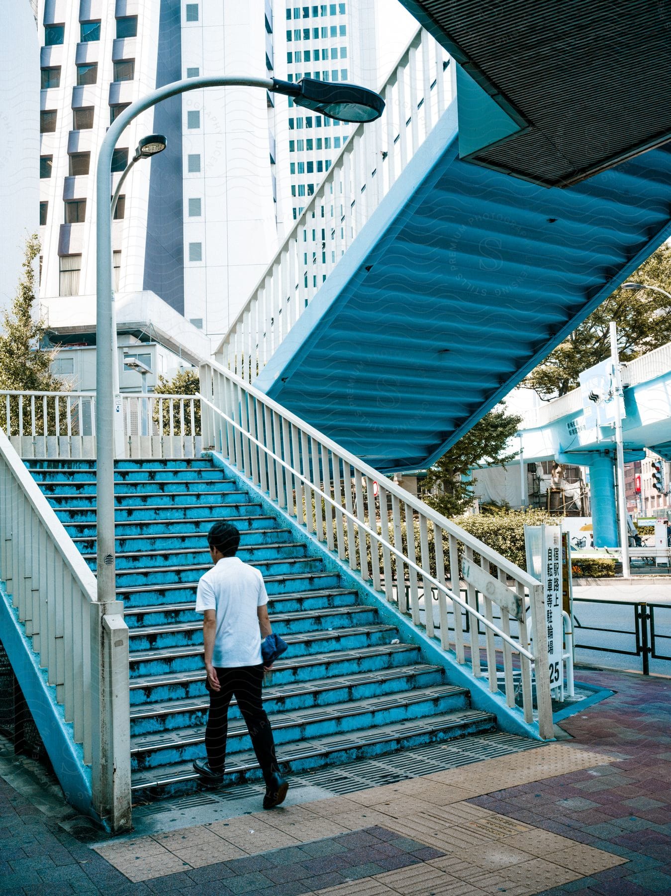 Man walking on a bluecolored staircase with a modern building in the background