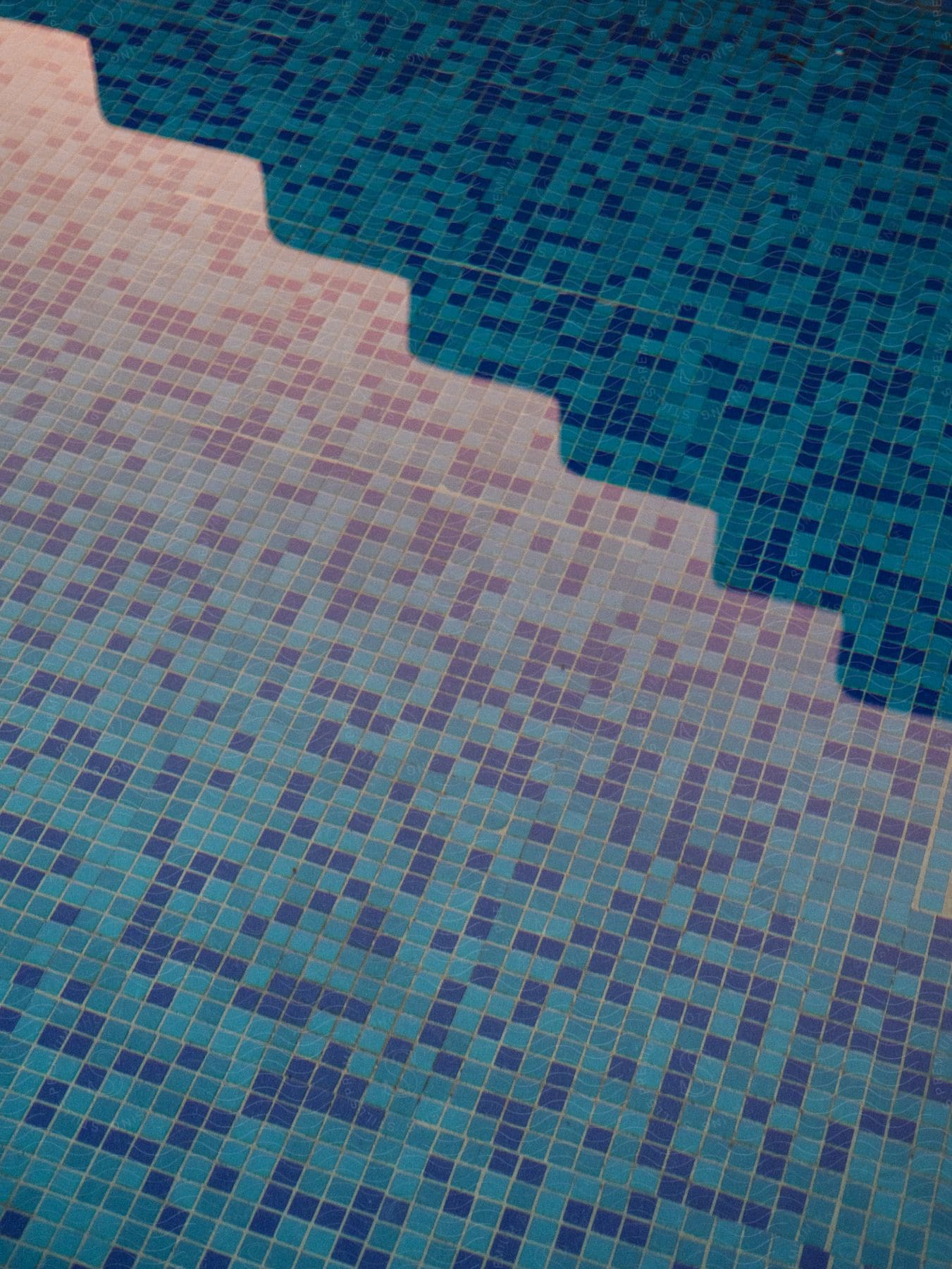 Filled swimming pool with a floor made of squares in varying shades of blue