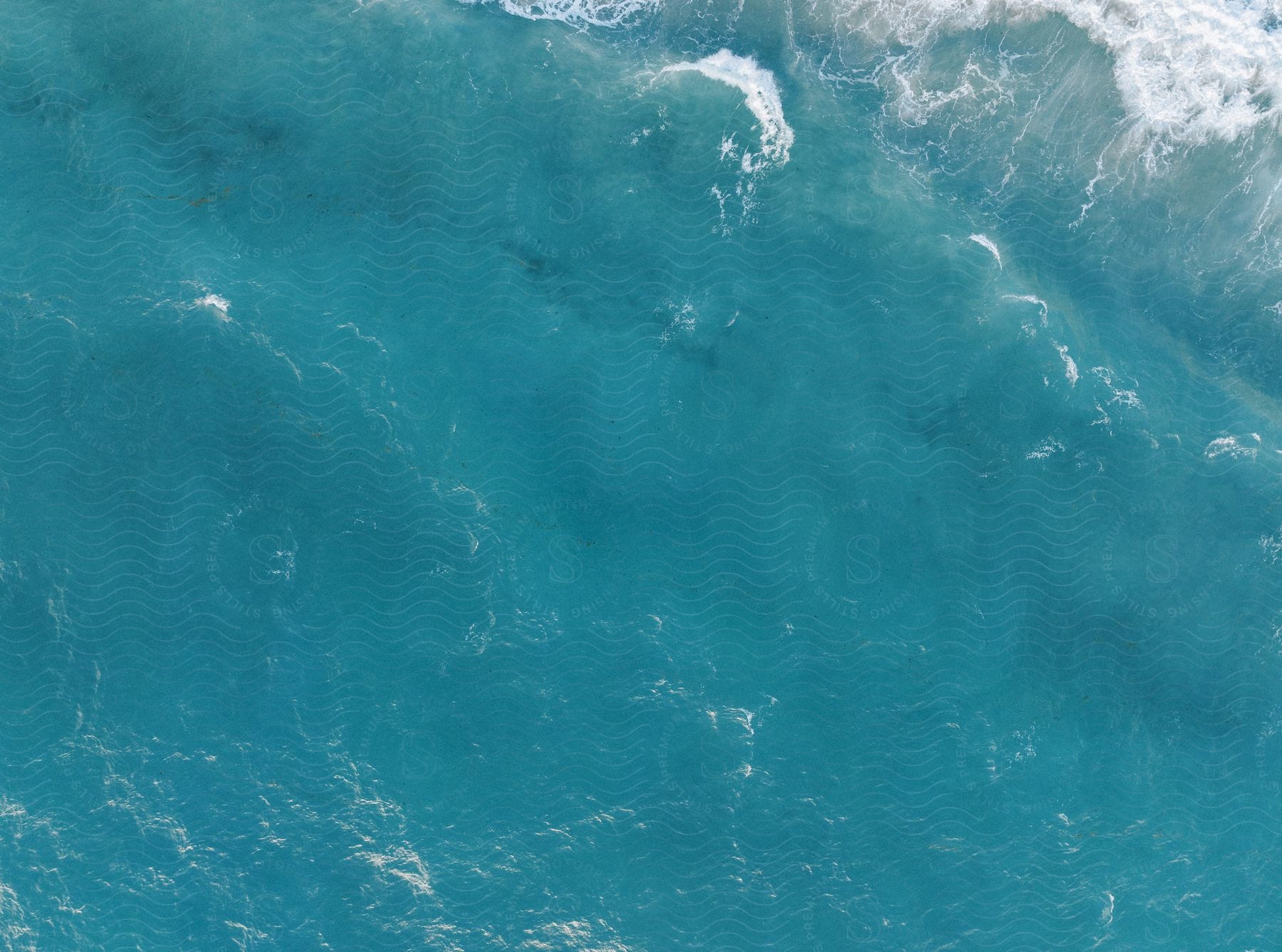 Clear blue water splashes with reflected light on ripples and waves