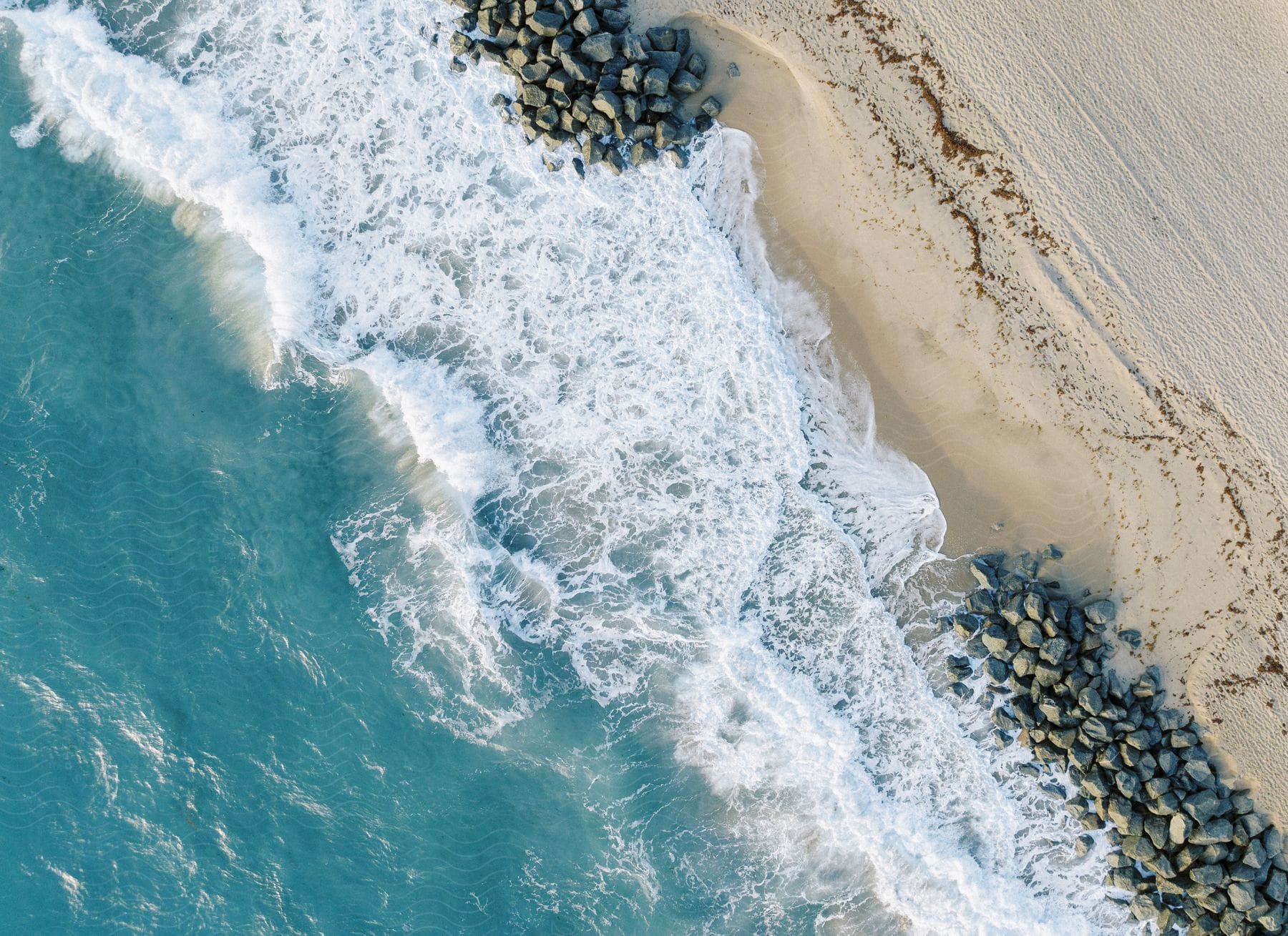 Aerial beach with white sand and rocks on the shore