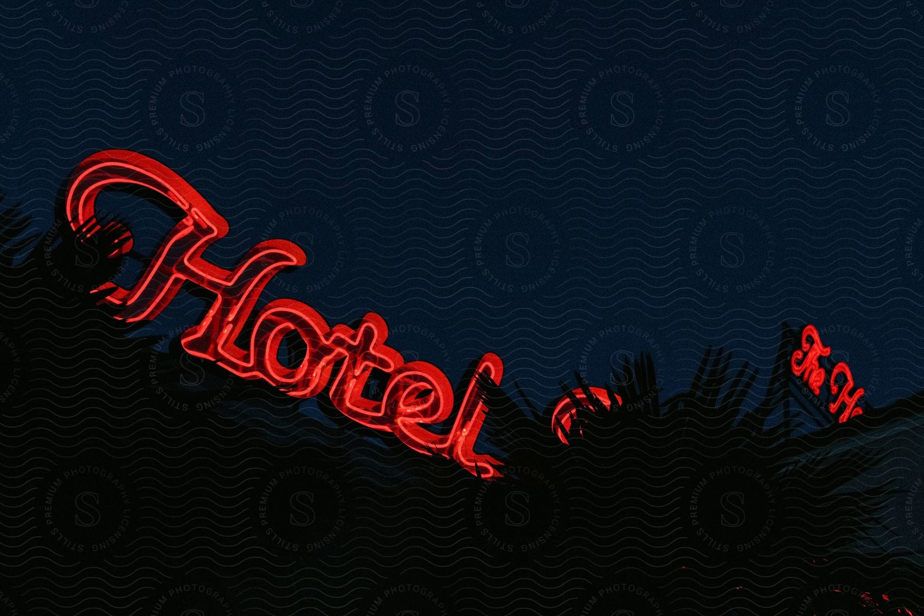 A hotels neon sign glowing brightly in the night