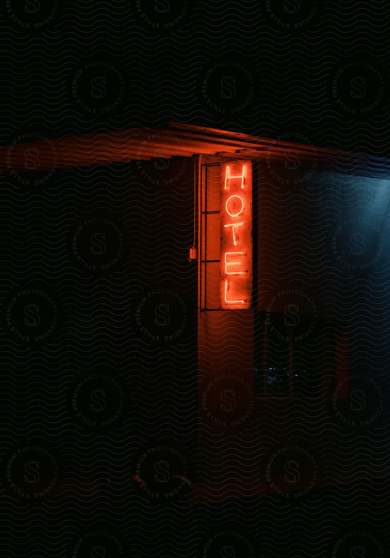 A dark hotel with only a red signpost light on