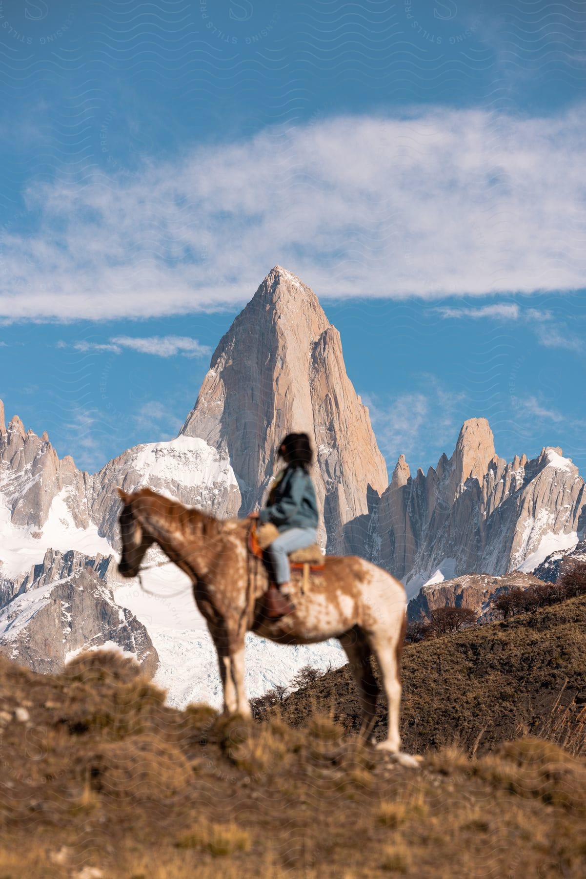 A woman riding a horse near mountains