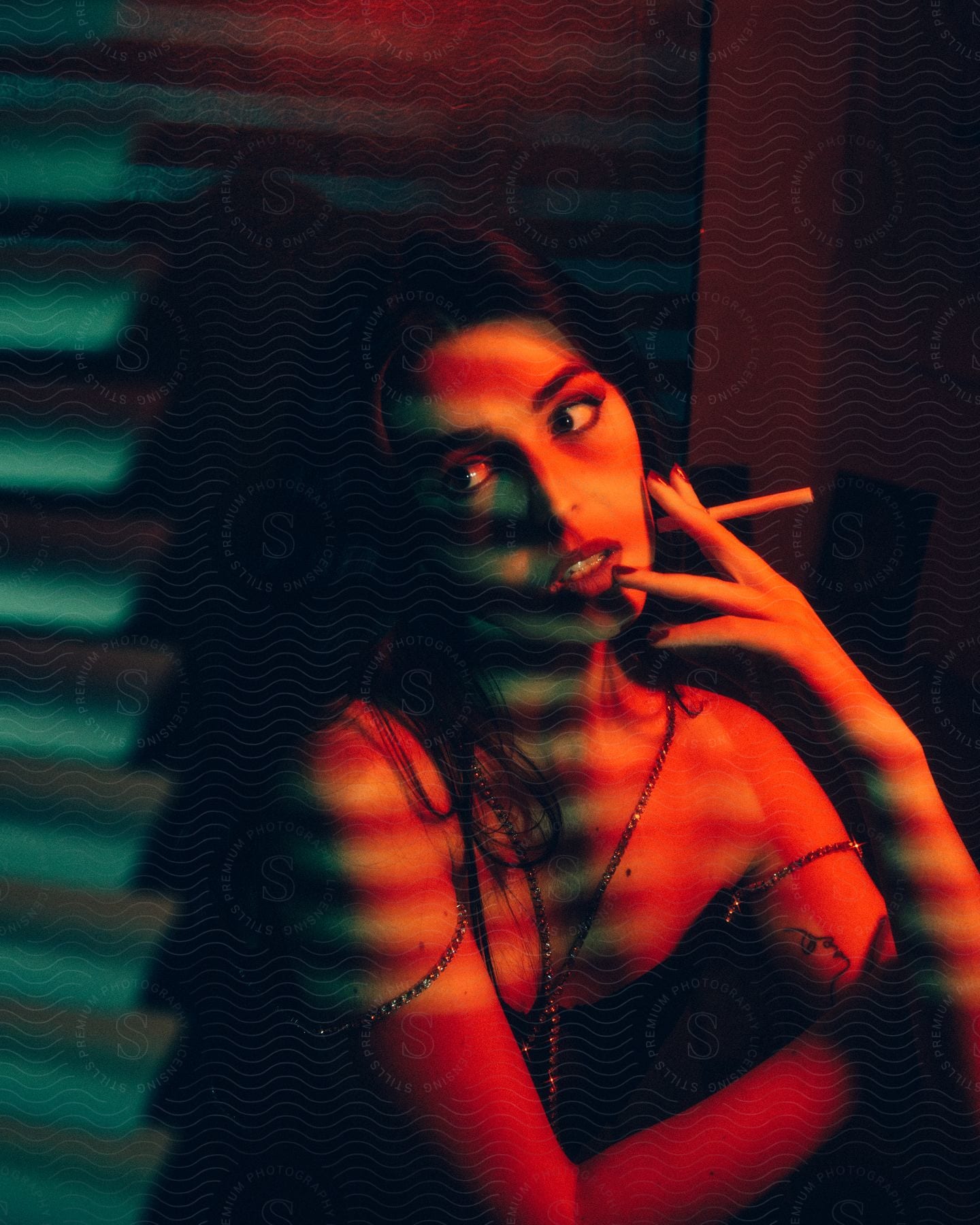 Young brunette woman posing with a cigarette under colorful lights