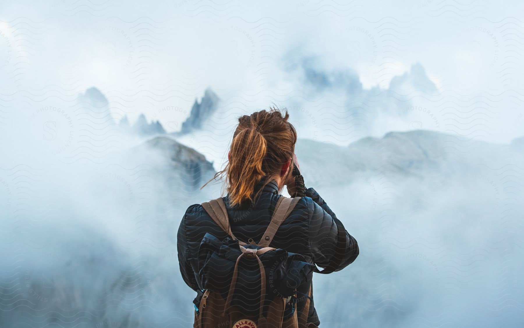 A backpacker pauses to admire mountains enveloped in clouds