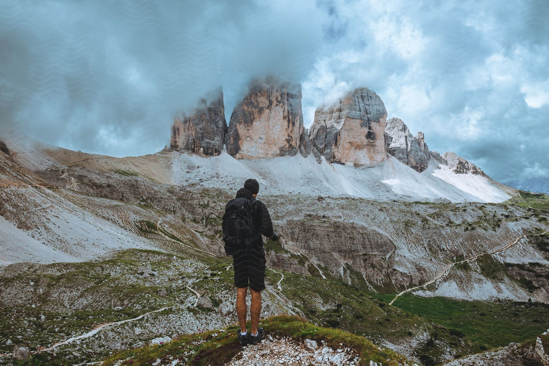 Hiker stands against tre cime di lavaredo mountain range