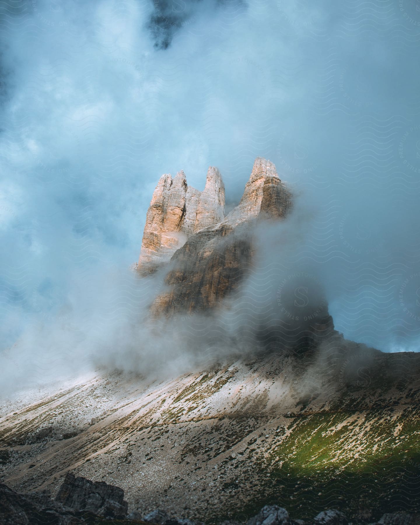 Clouds cover rock formations on a mountain under a sunny sky